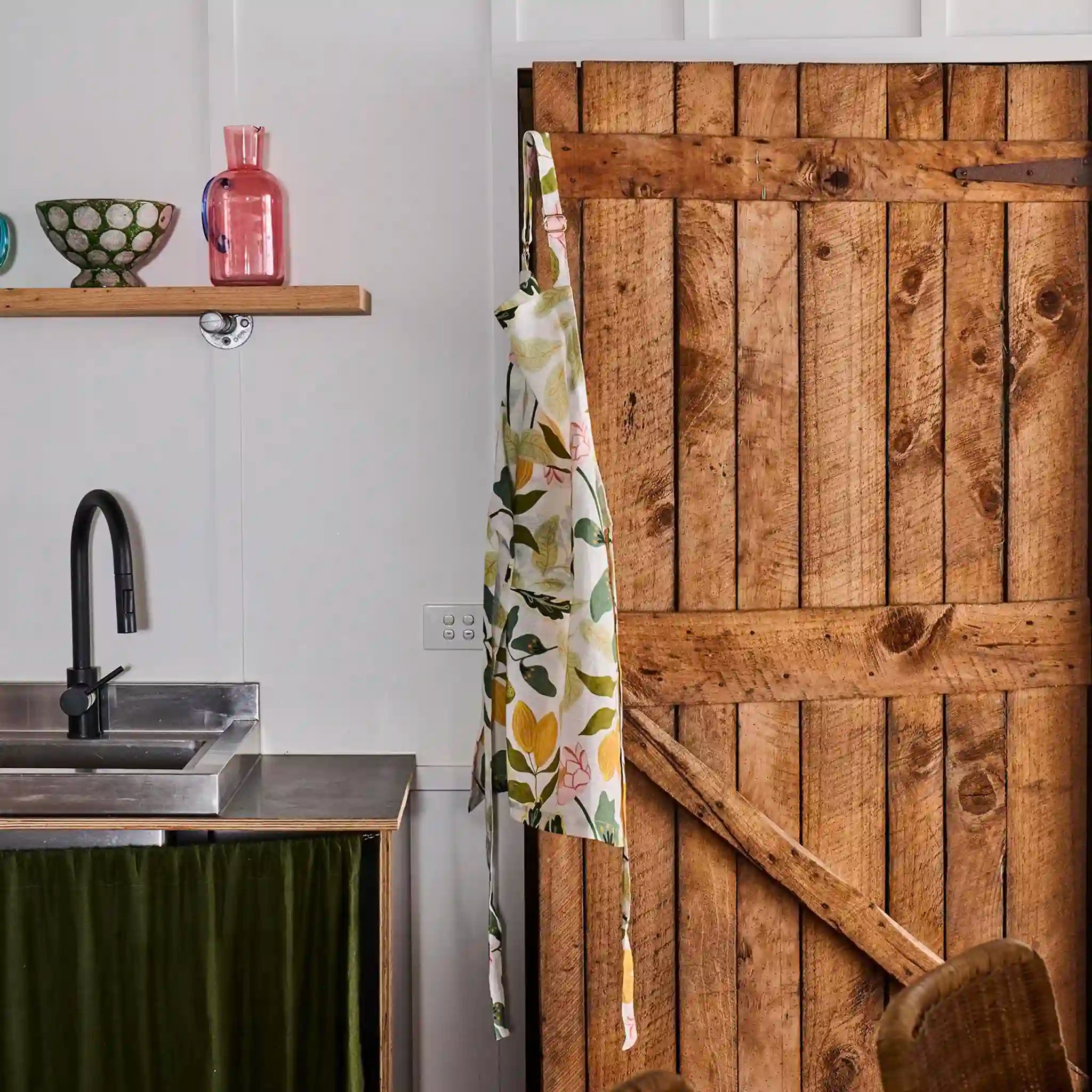 Kitchen with wooden door, sink, and shelf with decorative items.