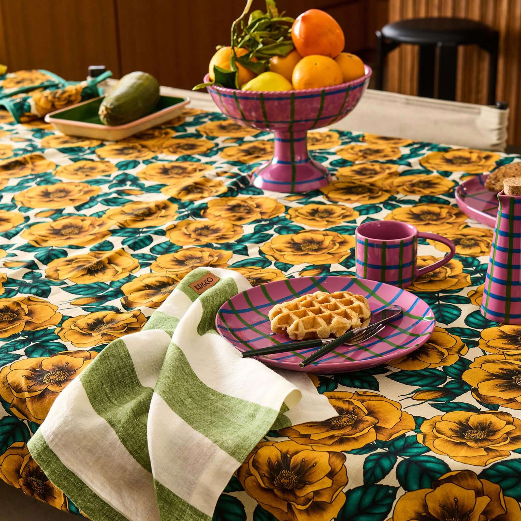 Alt Tag: Kip & Co Linen & Cotton Tablecloth - Golden Peony on dining table with golden peony floral print, fruit bowl and breakfast set