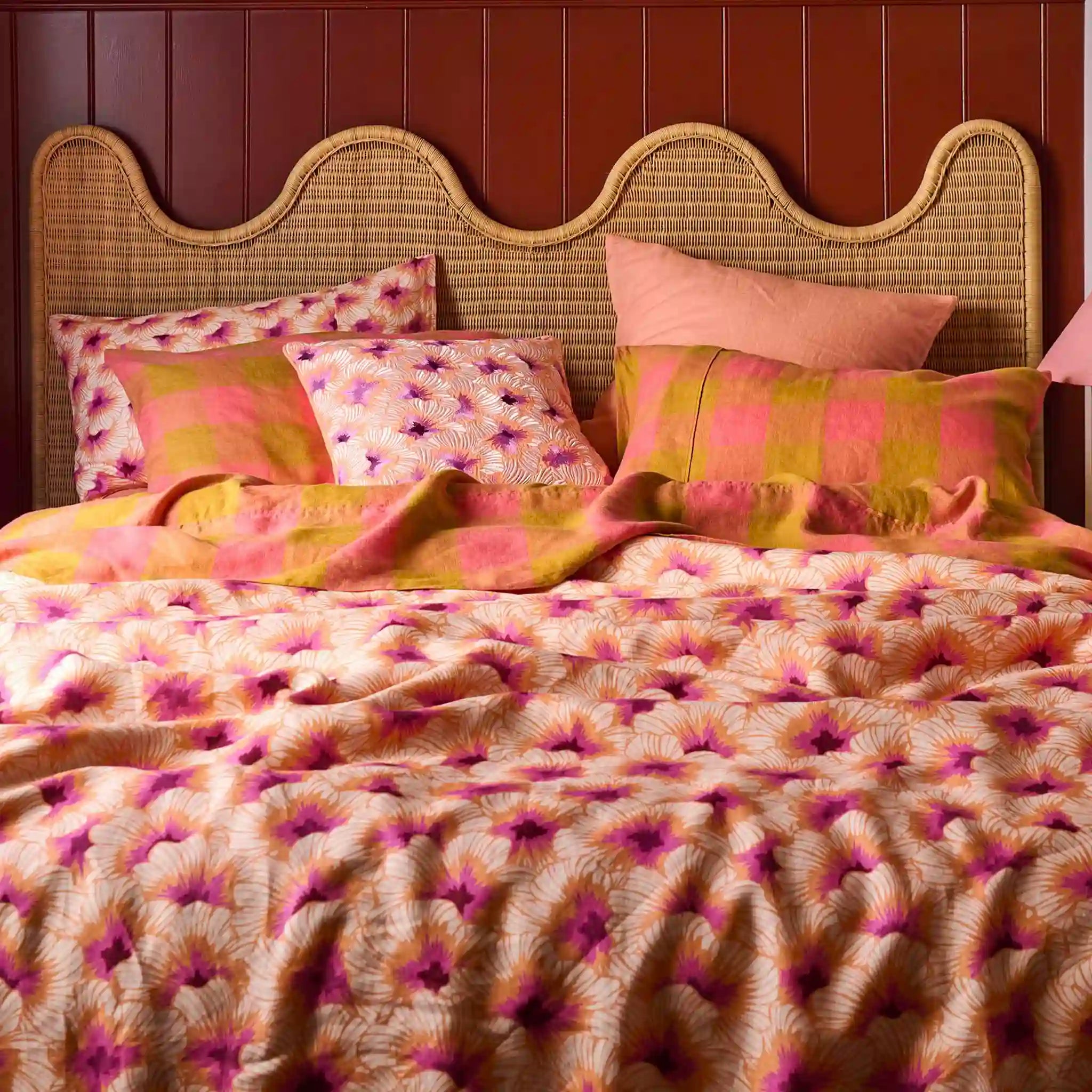 Bed with floral bedding and pillows against a wooden panel wall