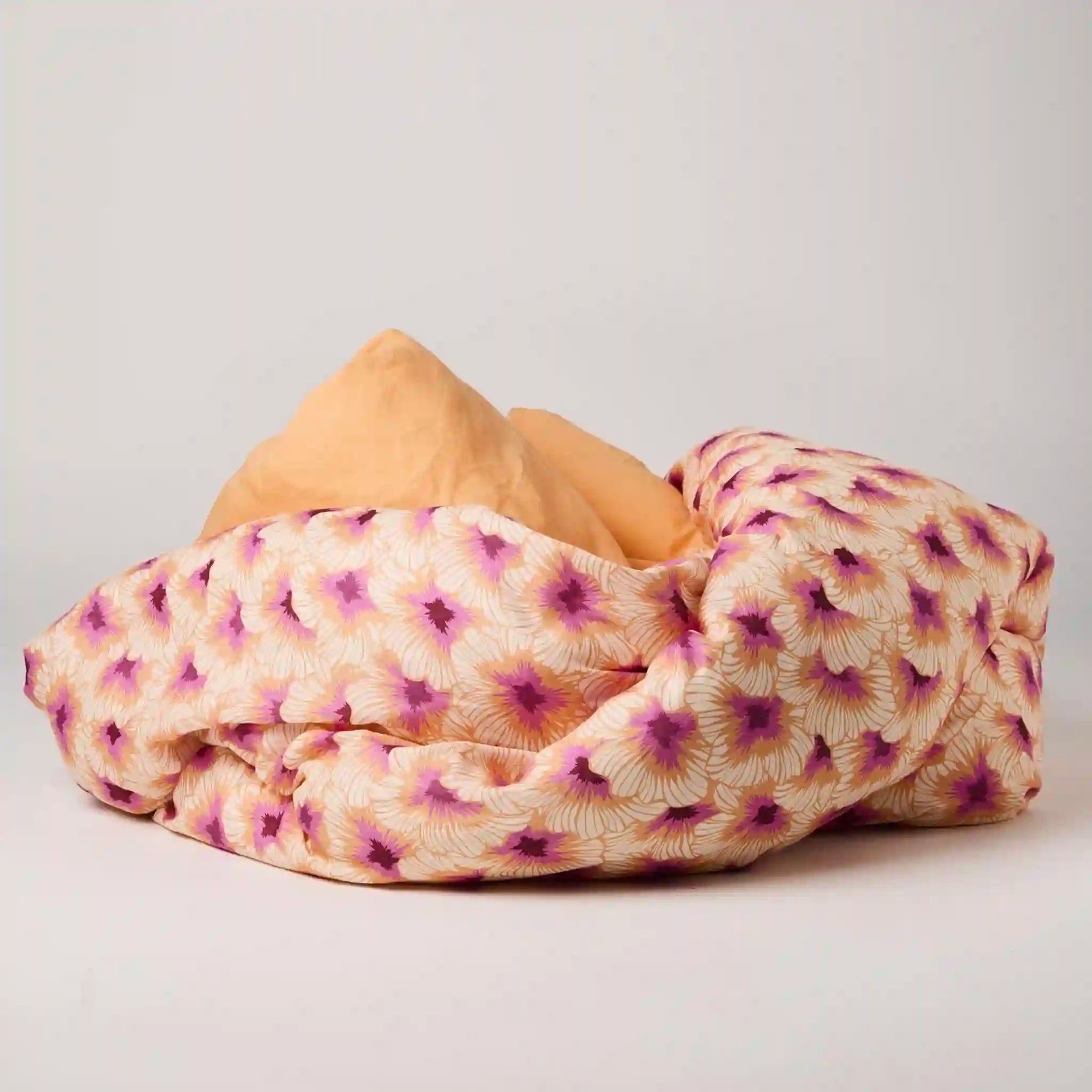 Folded floral blanket with purple and pink patterns on a light gray background