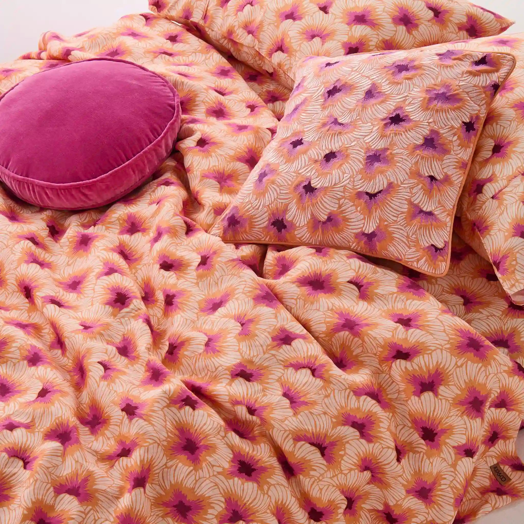 Floral patterned bedding set with pink and purple colors on a bed.