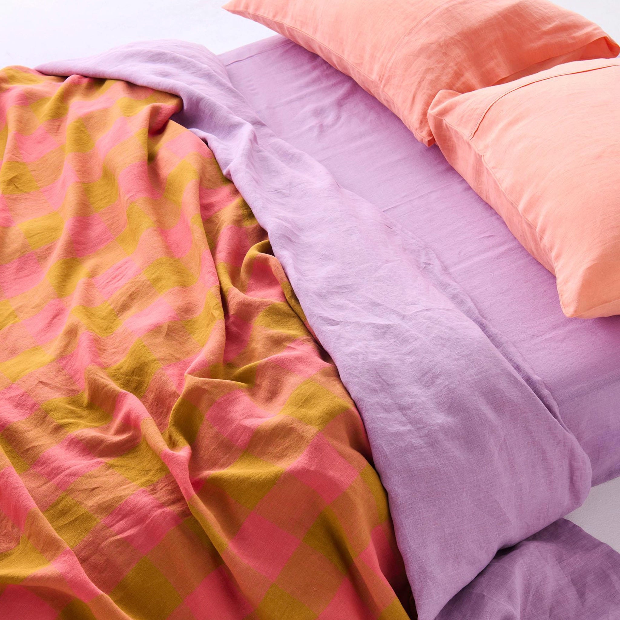 Colorful bedding with pink, purple, and yellow patterns on a bed.