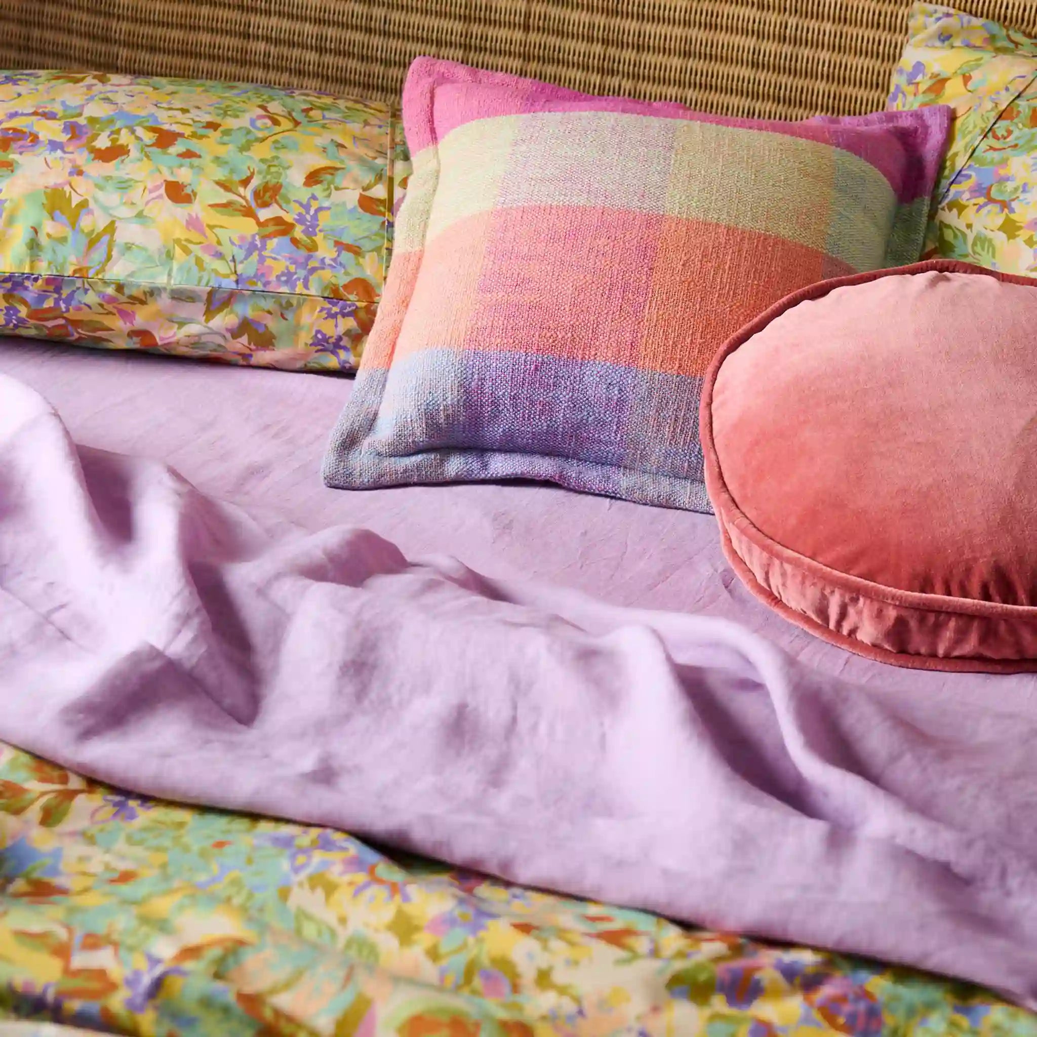 Colorful pillows and blanket on a floral-patterned sofa