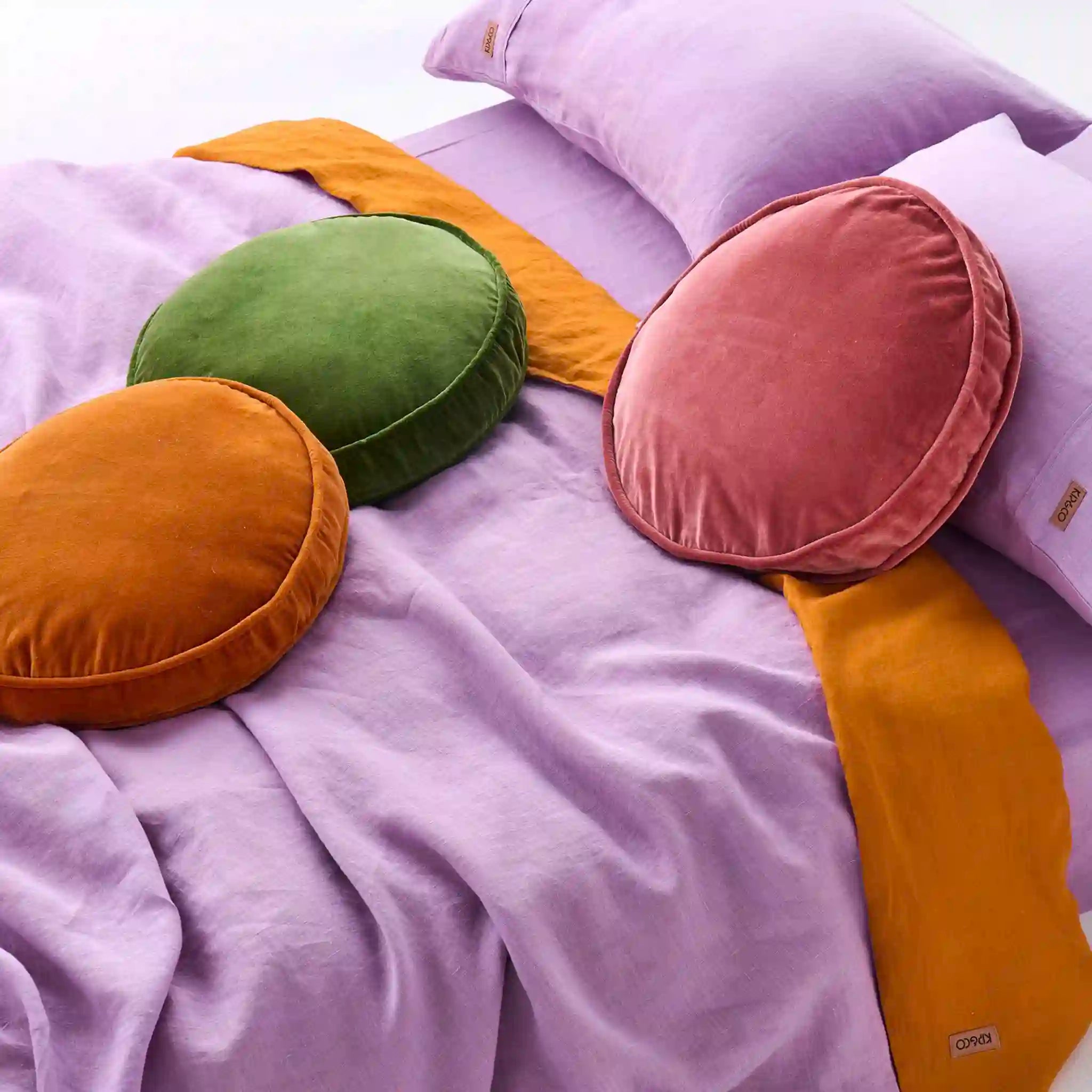 Colorful round cushions on a purple bedspread
