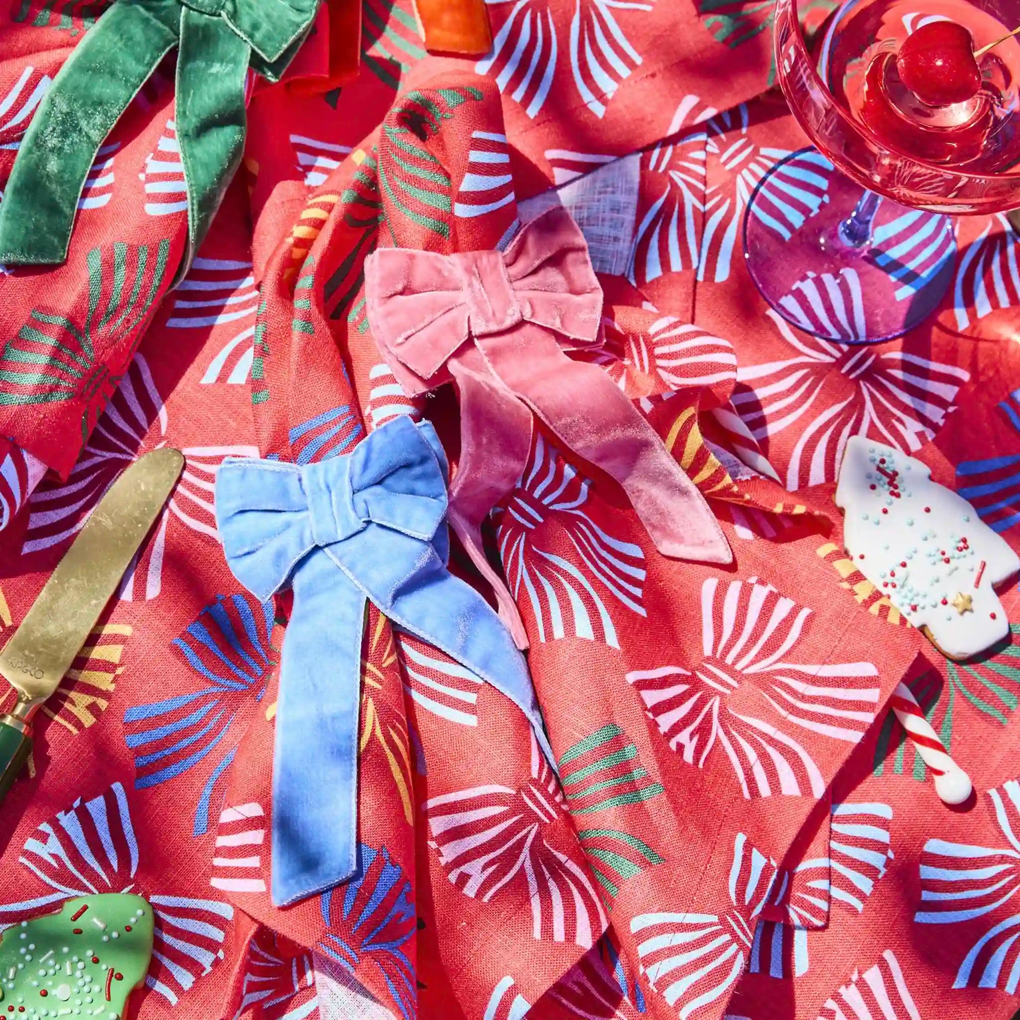 Colorful table setting with bow-knotted napkins on a patterned tablecloth.
