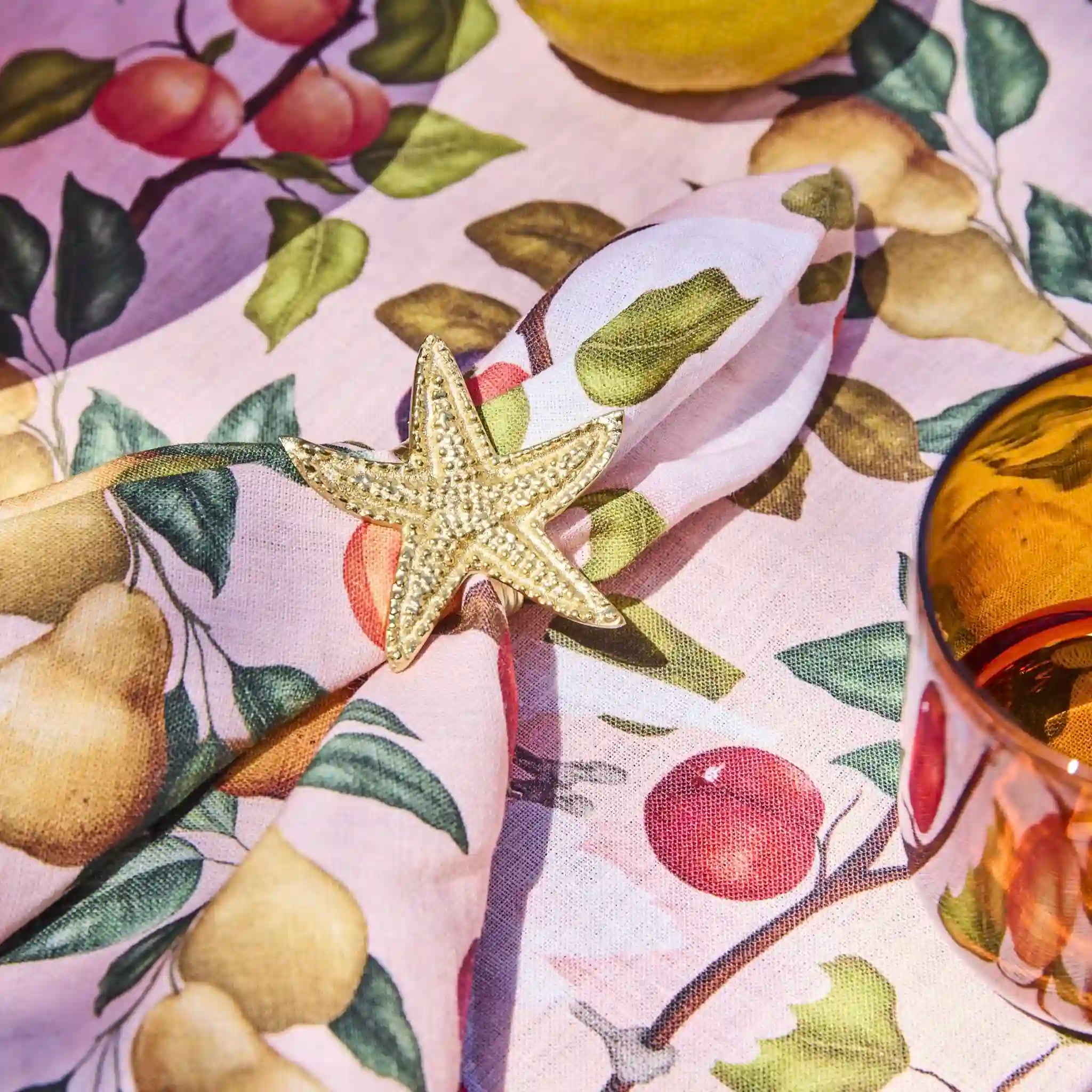 Gold star-shaped ring on a colorful fabric background with fruit design