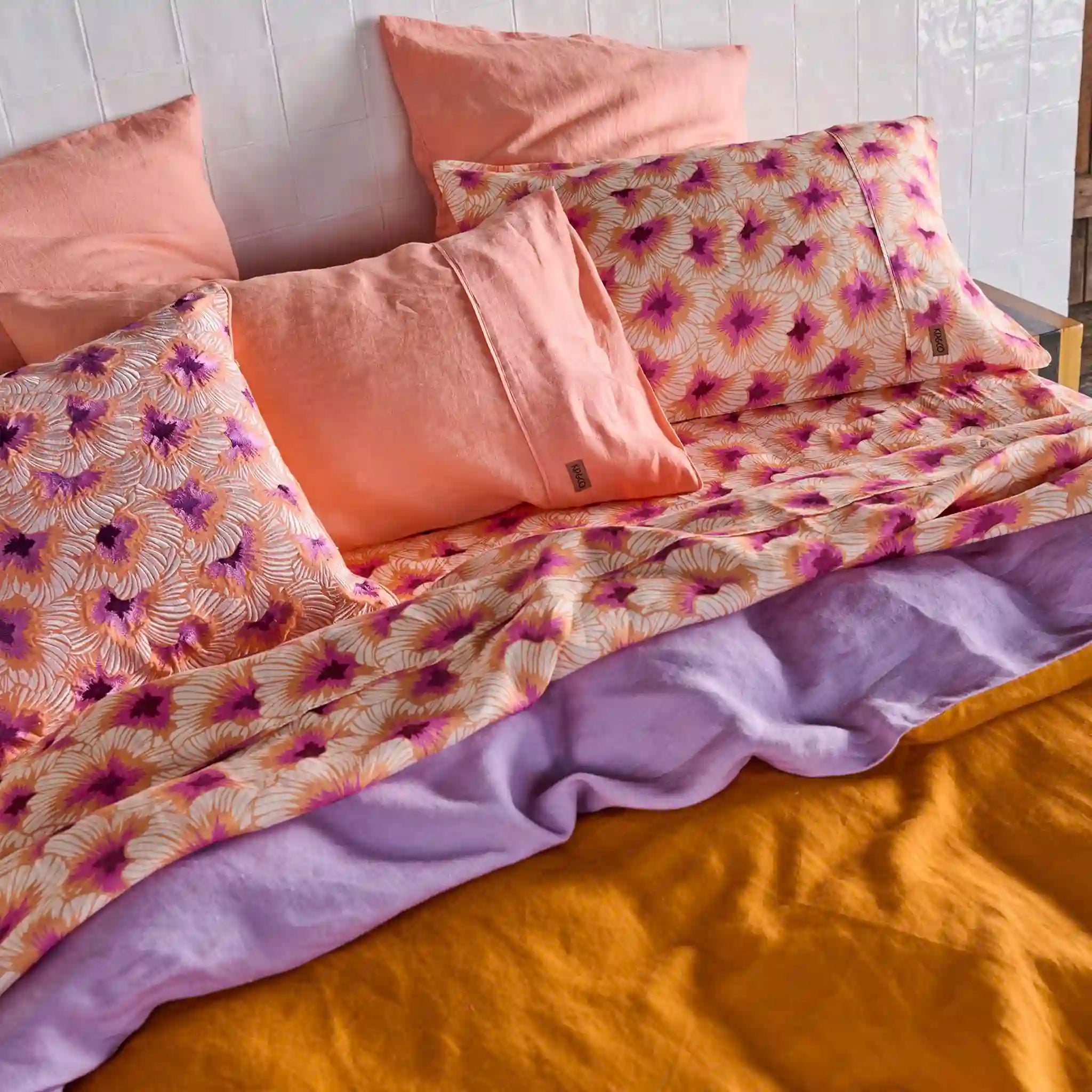 Floral patterned bedding with pink, purple, and orange colors on a bed.
