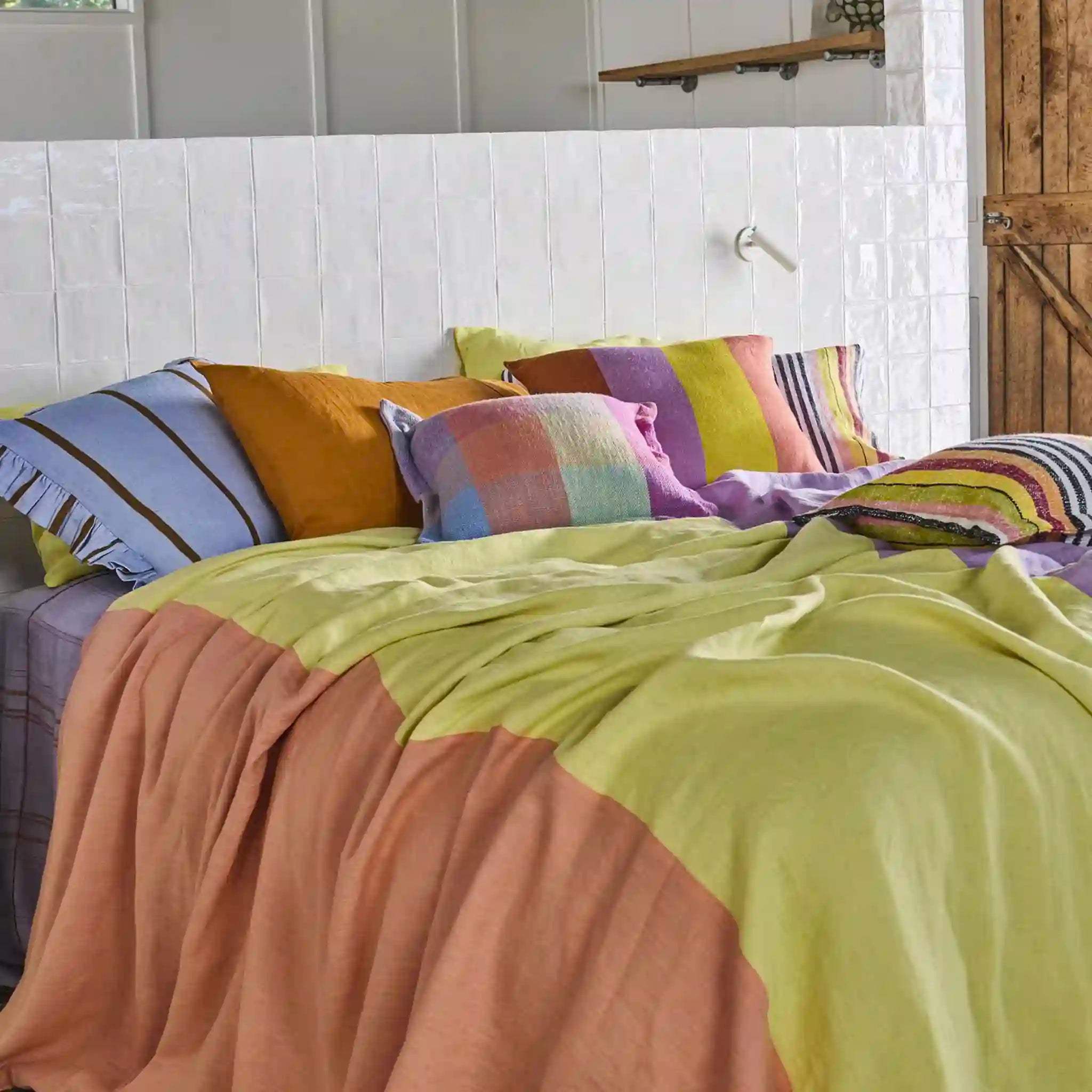 Colorful bedding set on a bed with a wooden headboard.