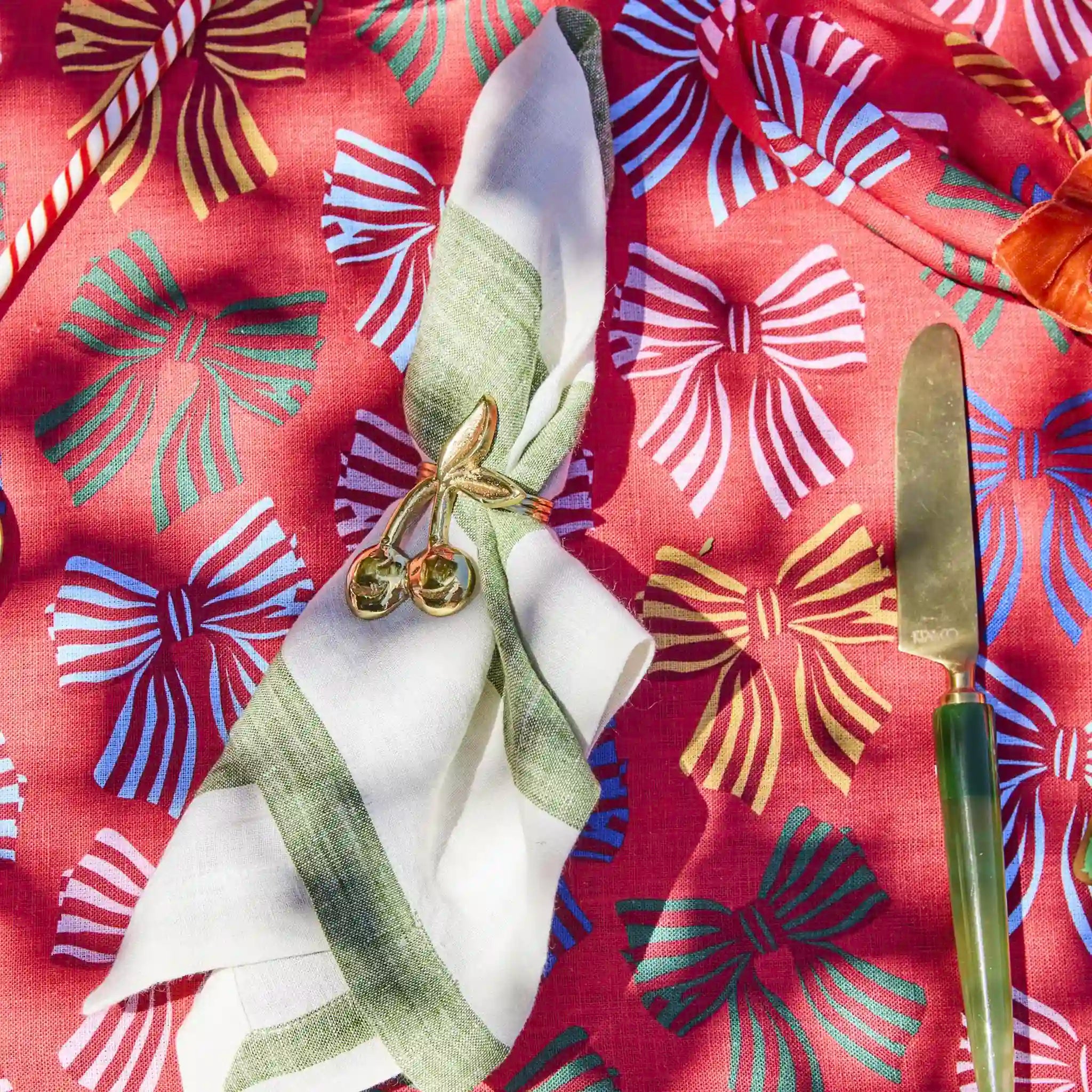 Napkin with decorative bow and knife on a red fabric background with colorful bow patterns