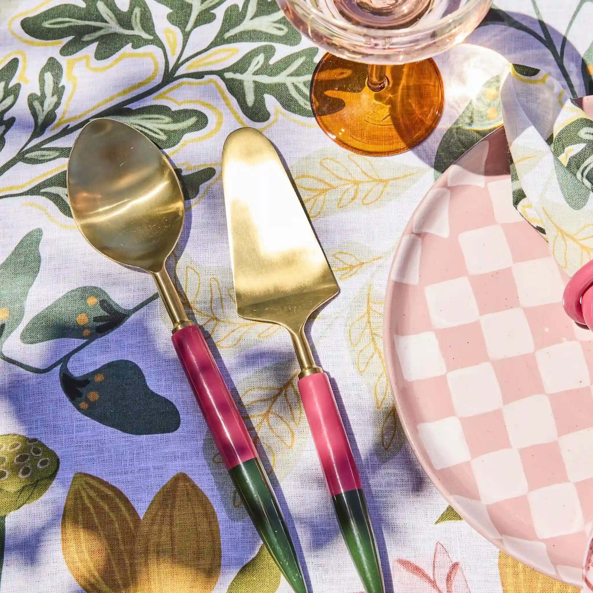 Gold cutlery with colorful handles on a patterned tablecloth