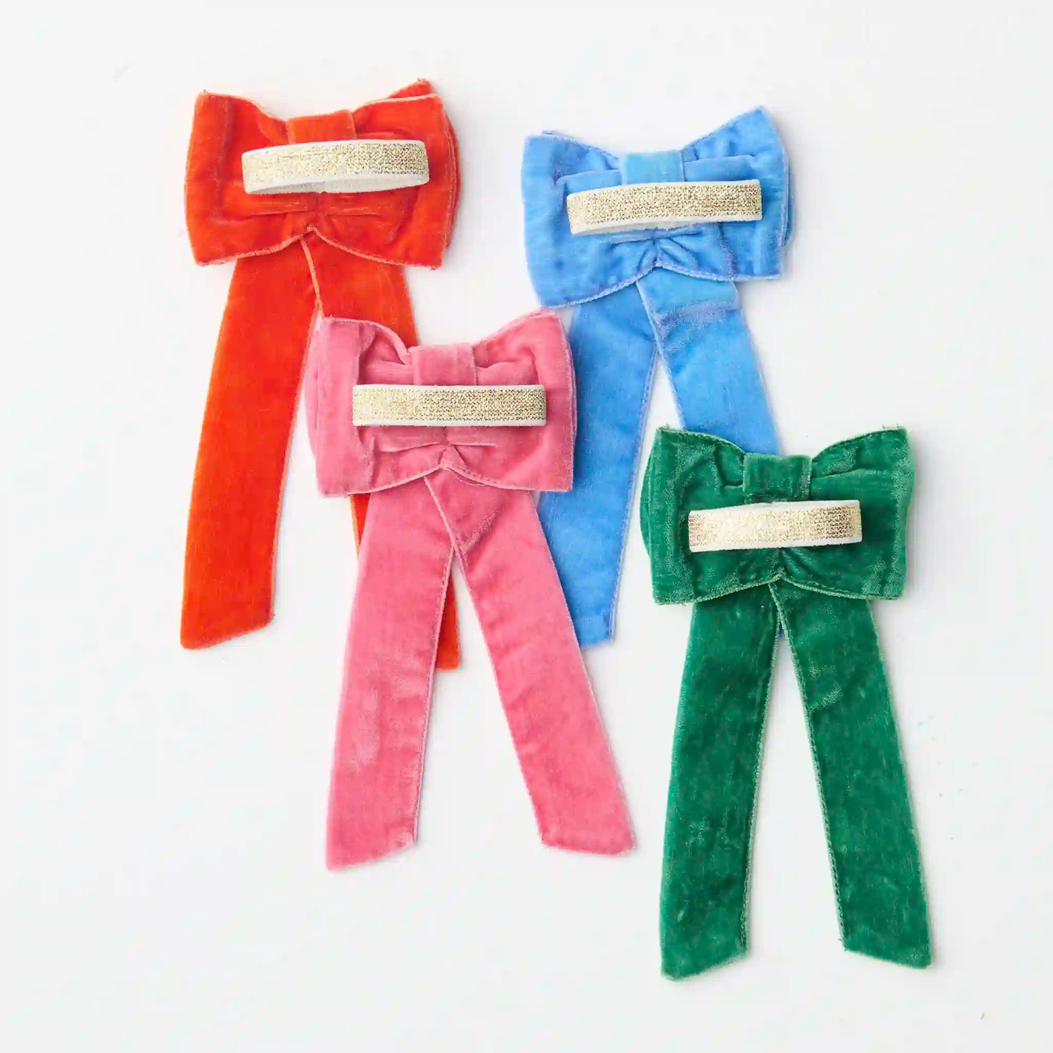 Four colorful velvet bows with gold centers on a white background