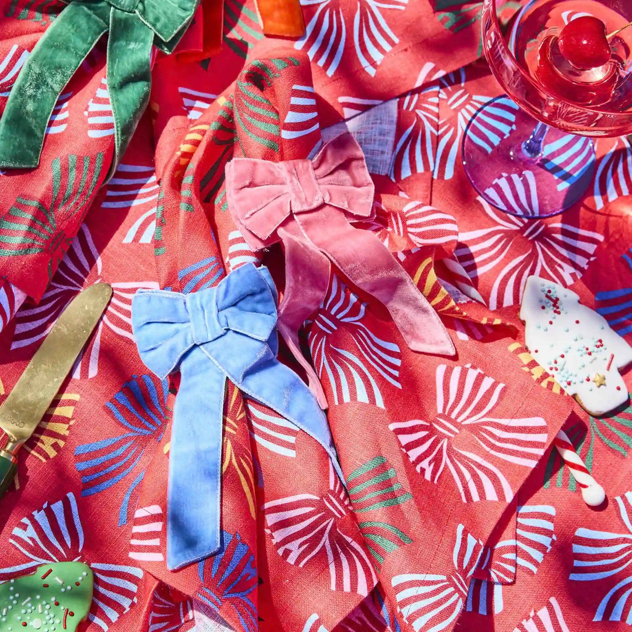 Colorful fabric with bow patterns and a glass of juice on a red floral background