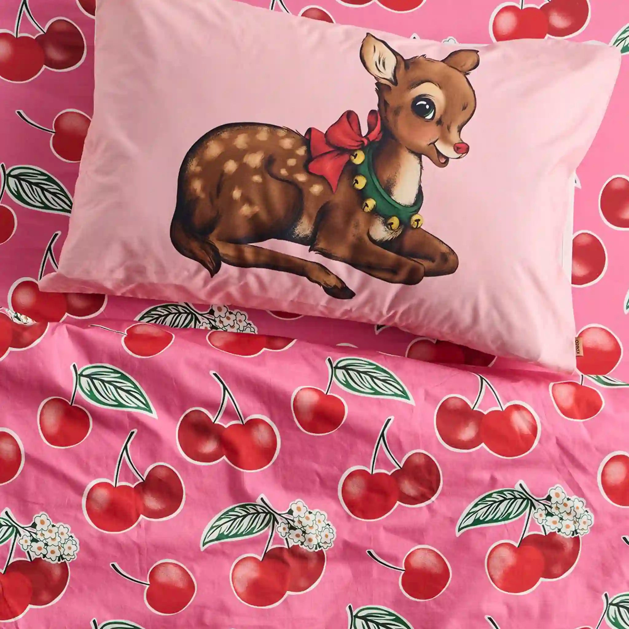 Pink pillowcase with a cartoon deer wearing a bow, on a pink background with cherry pattern