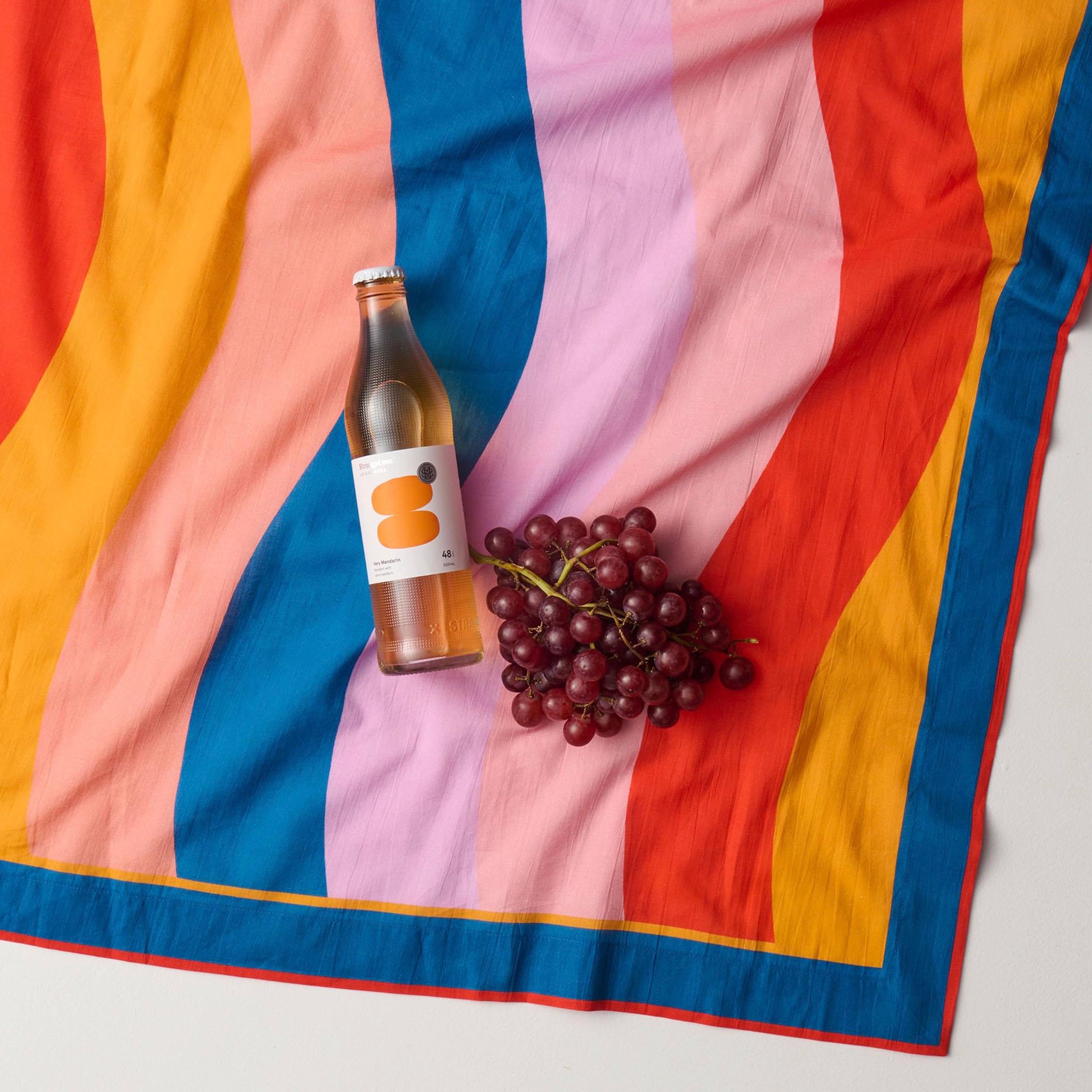 Bottle with a label and bunch of grapes on a colorful striped sarong