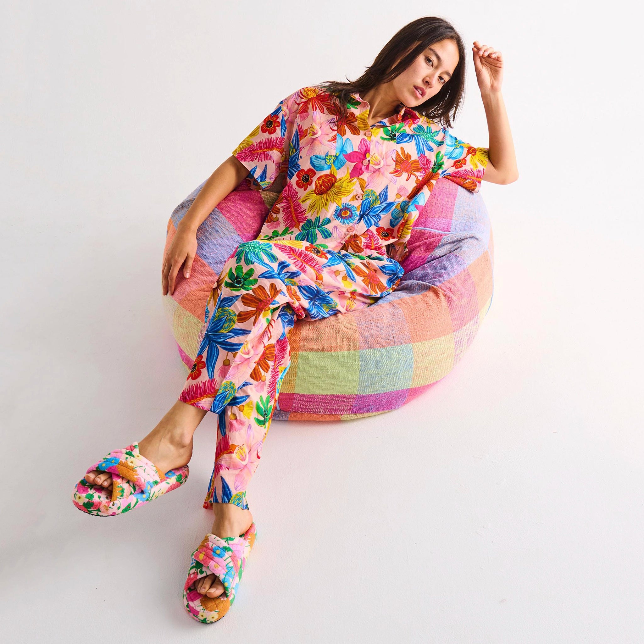 Woman in a colorful outfit sitting on a bean bag chair against a white background