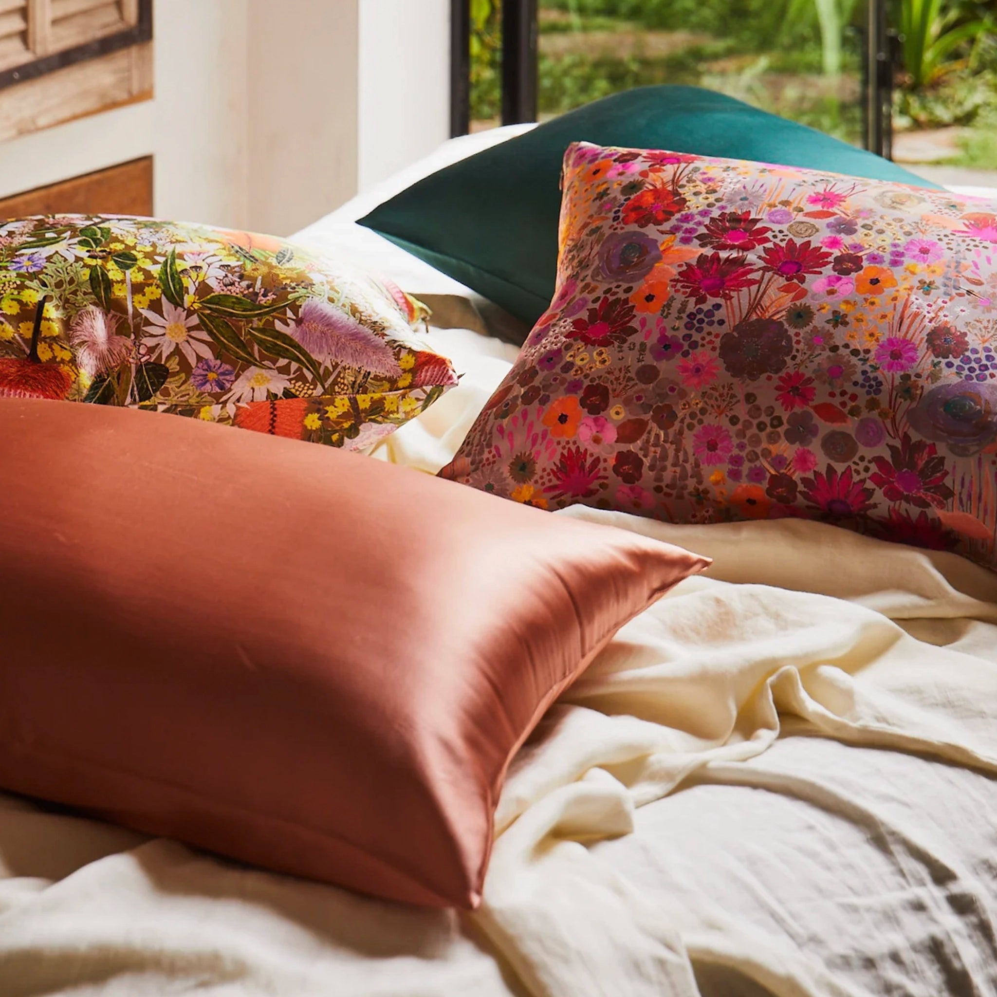 Floral patterned pillows on a bed with a blurred outdoor background