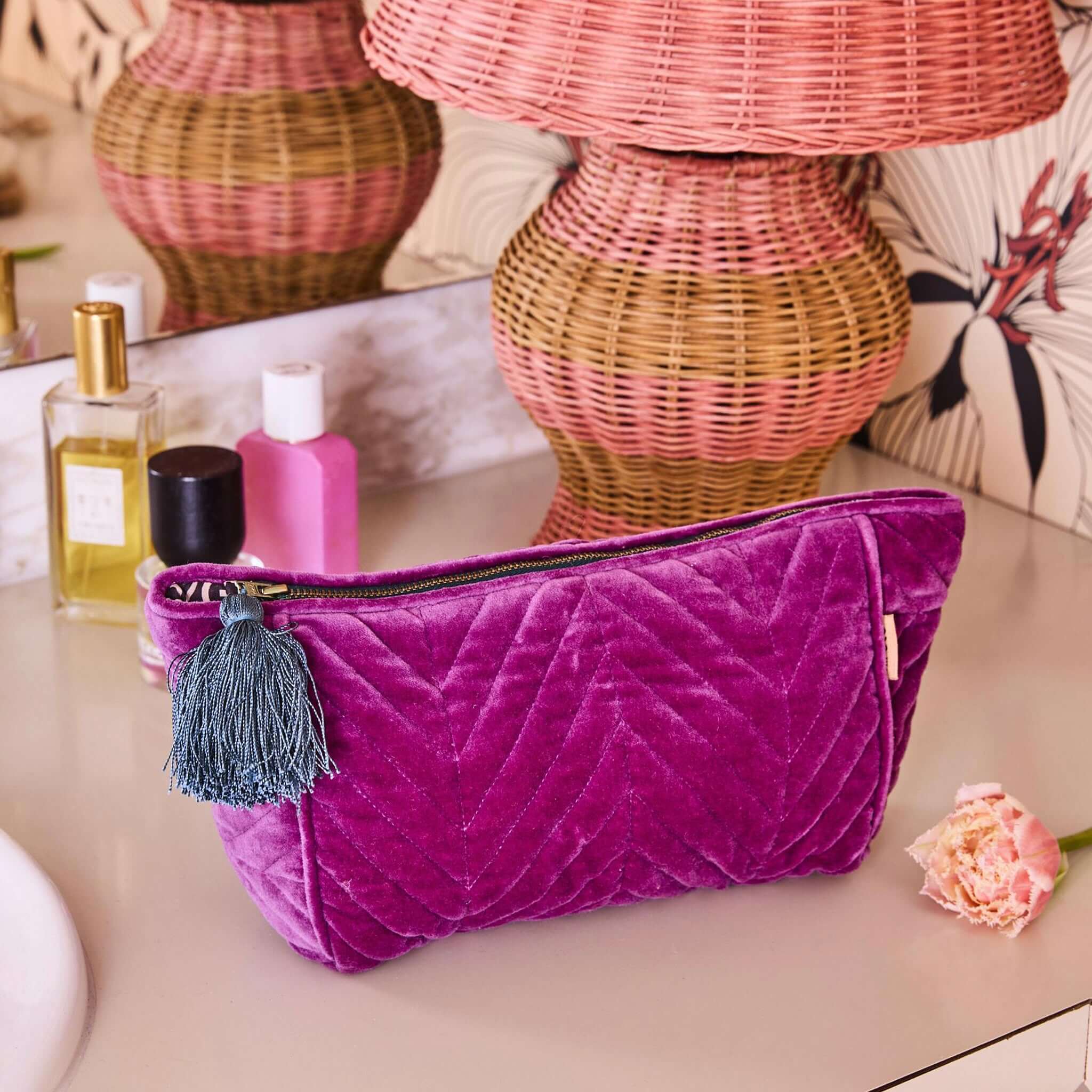 Alt Tag: Kip & Co Velvet Toiletry Bag - Wild Grape purple cotton velvet cosmetic bag with blue tassel on vanity
