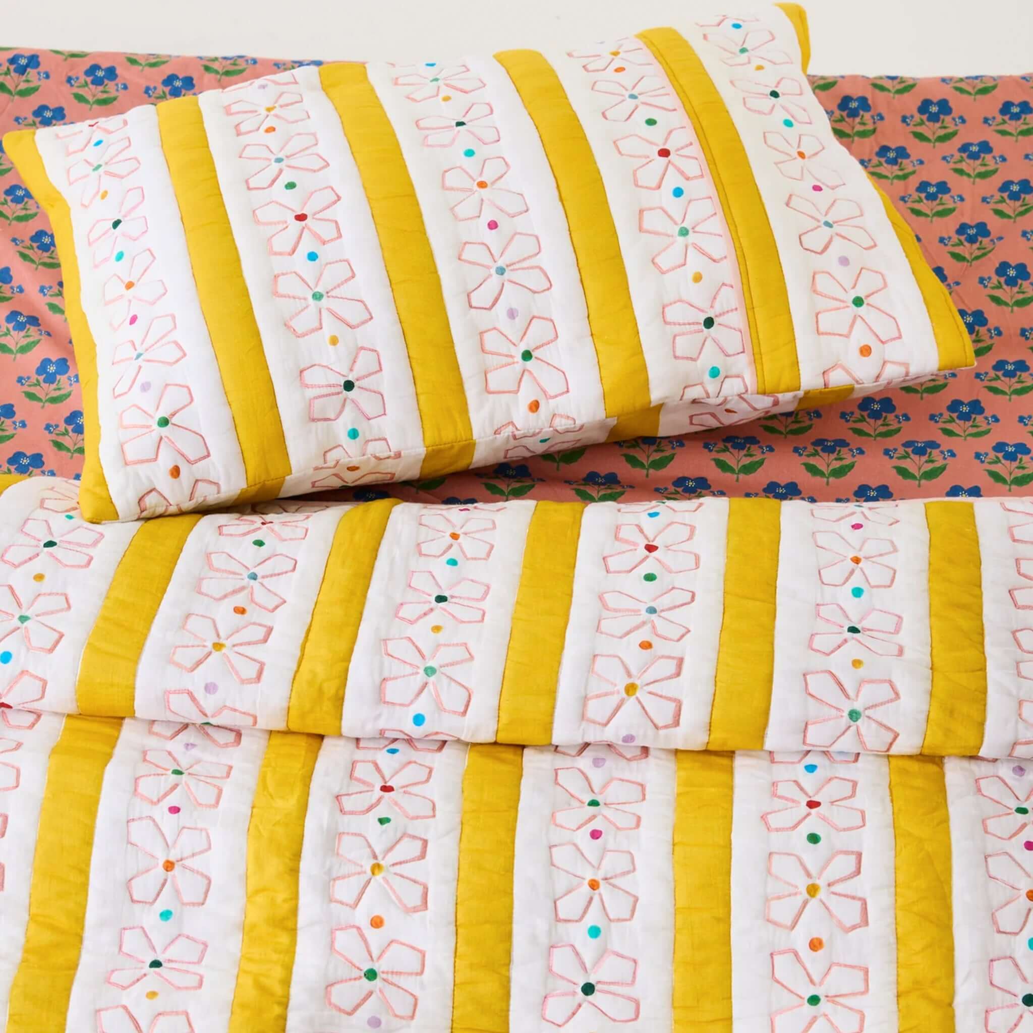 Kip & Co x Anna Spiro Daisy Chain Organic Cotton Quilted Pillowslip on a colorful bedspread.