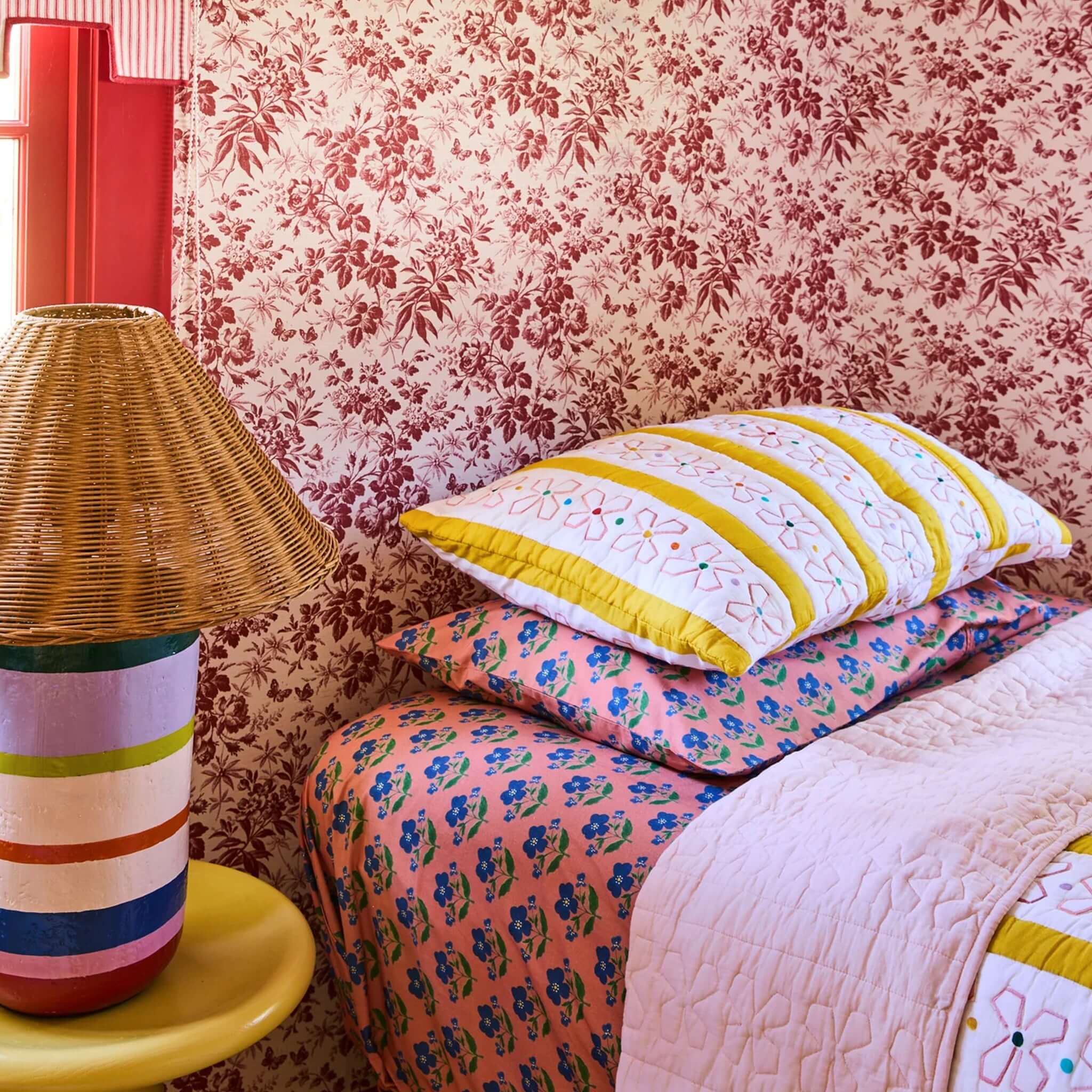 Kip & Co x Anna Spiro Daisy Chain Organic Cotton Quilted Pillowslip on colorful bedding with floral patterns.