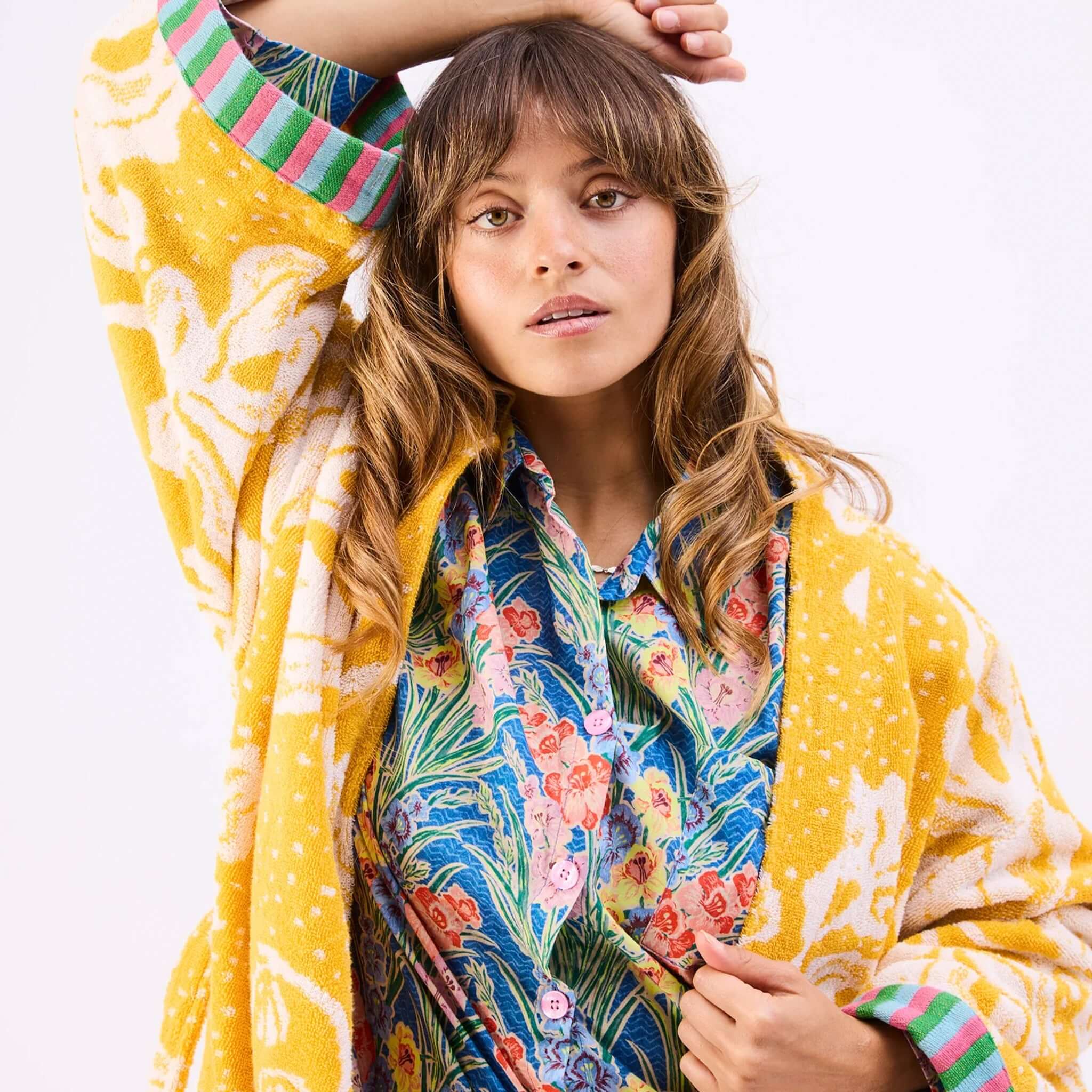 Kip & Co x Anna Spiro Elsternwig Fig Terry Bath Robe in vibrant yellow with floral patterns and colorful shirt underneath.