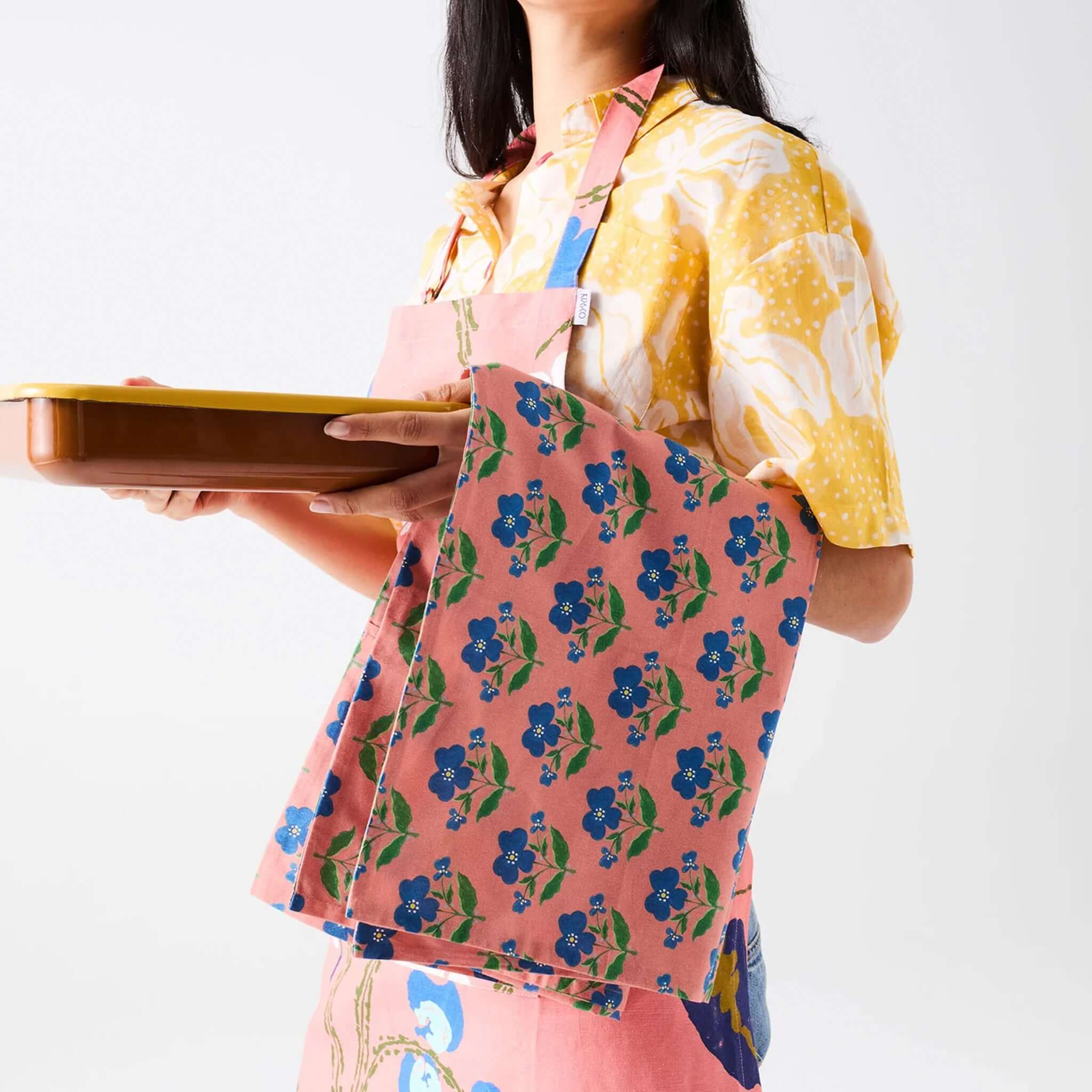Woman holding a tray wearing Kip & Co x Anna Spiro Linen & Cotton Tea Towel - Indian Summer Rose.