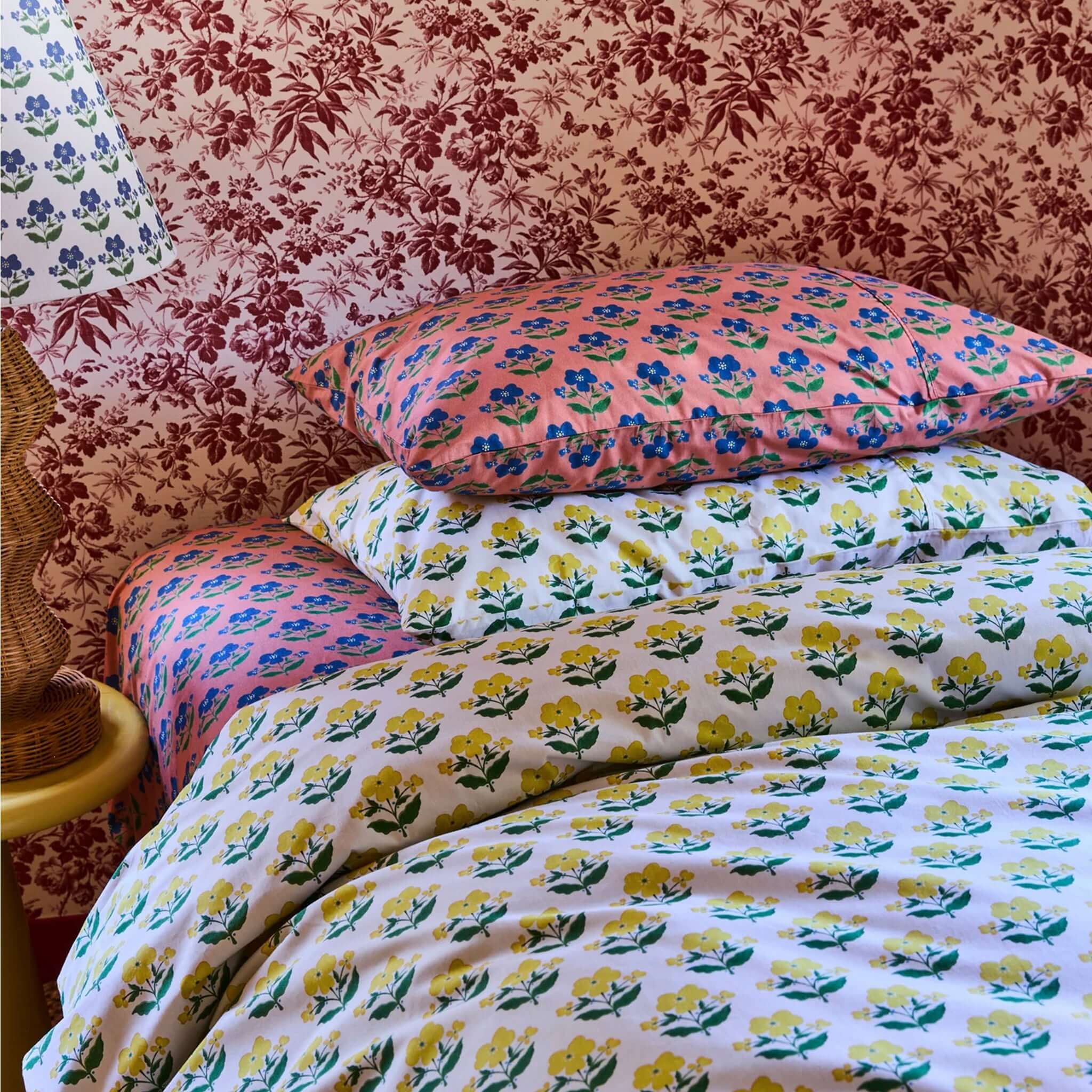 Kip & Co x Anna Spiro Organic Cotton Pillowslip Set - Indian Summer Rose on a bed with floral patterns and coordinating lamp.
