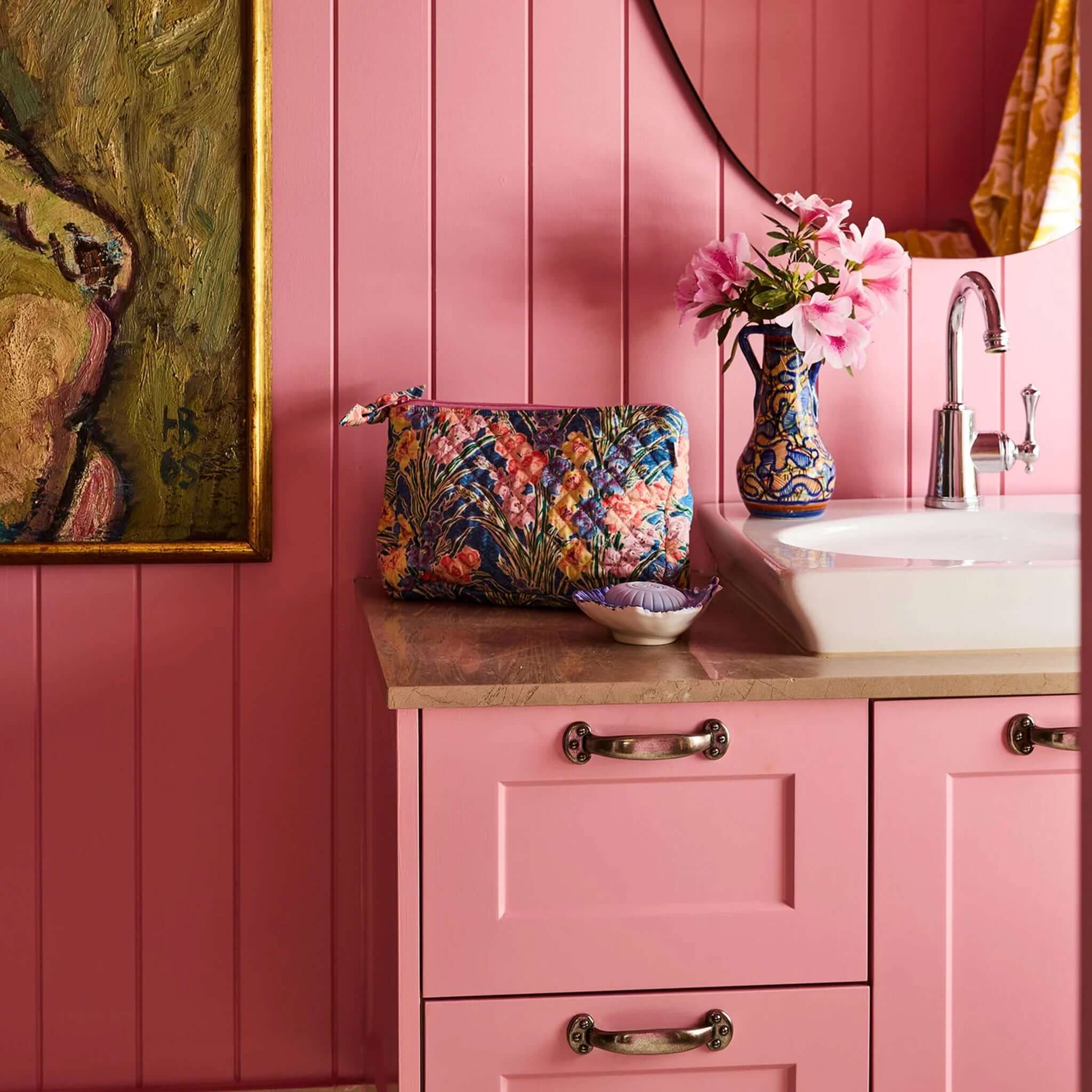 Kip & Co x Anna Spiro Quilted Toiletry Purse - Gladiolus on a pink bathroom countertop with flowers and art.