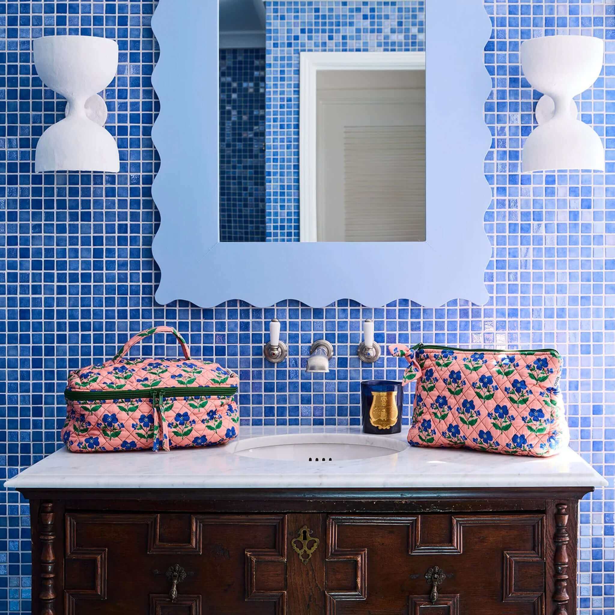 Kip & Co x Anna Spiro Quilted Toiletry Purse - Indian Summer Rose displayed on a marble bathroom sink.