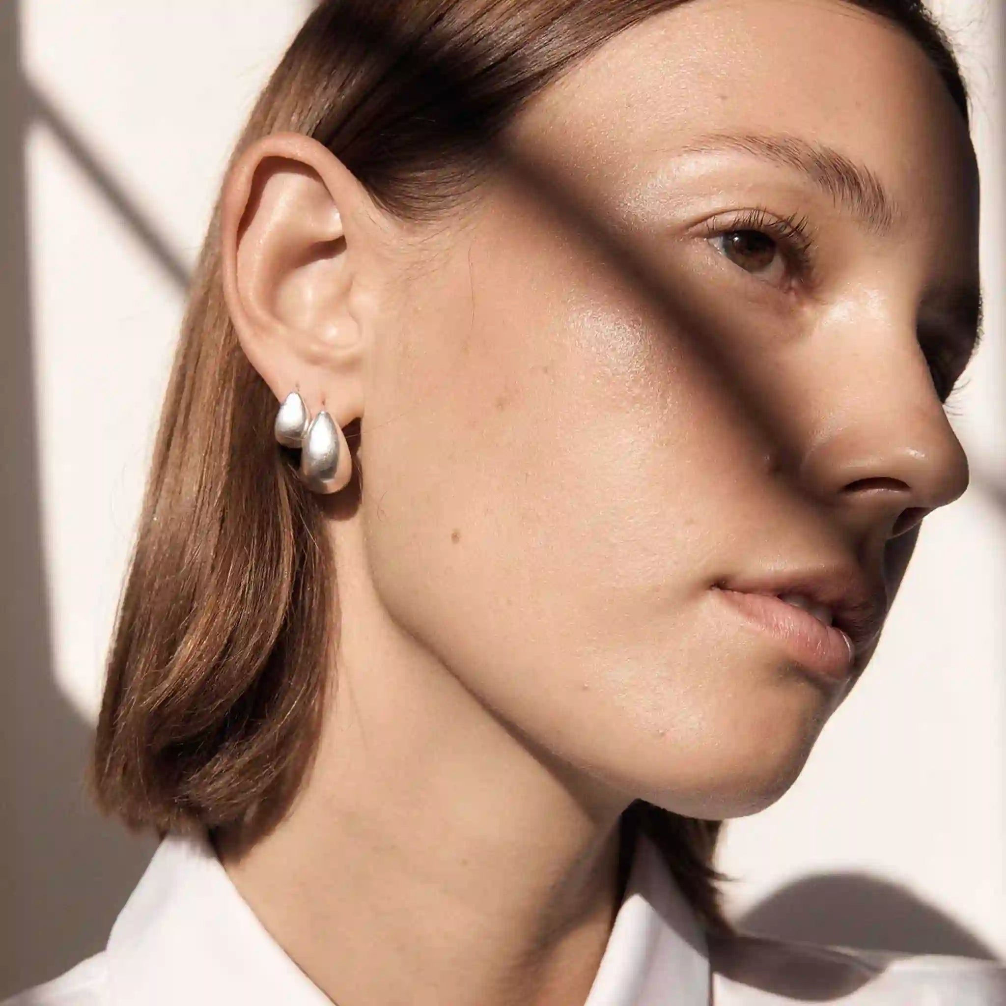 Close-up of a person wearing hoop earrings with a soft background