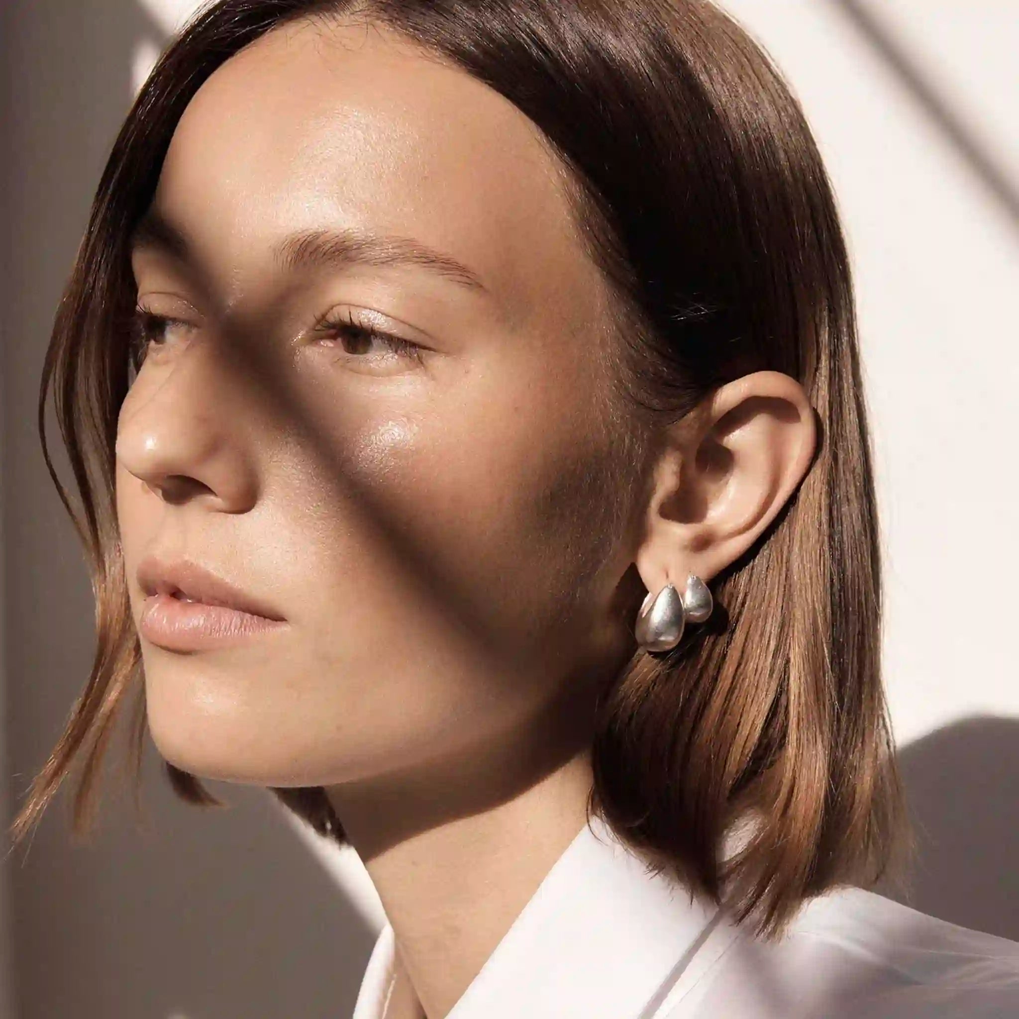 Close-up of a person wearing earrings with a neutral background