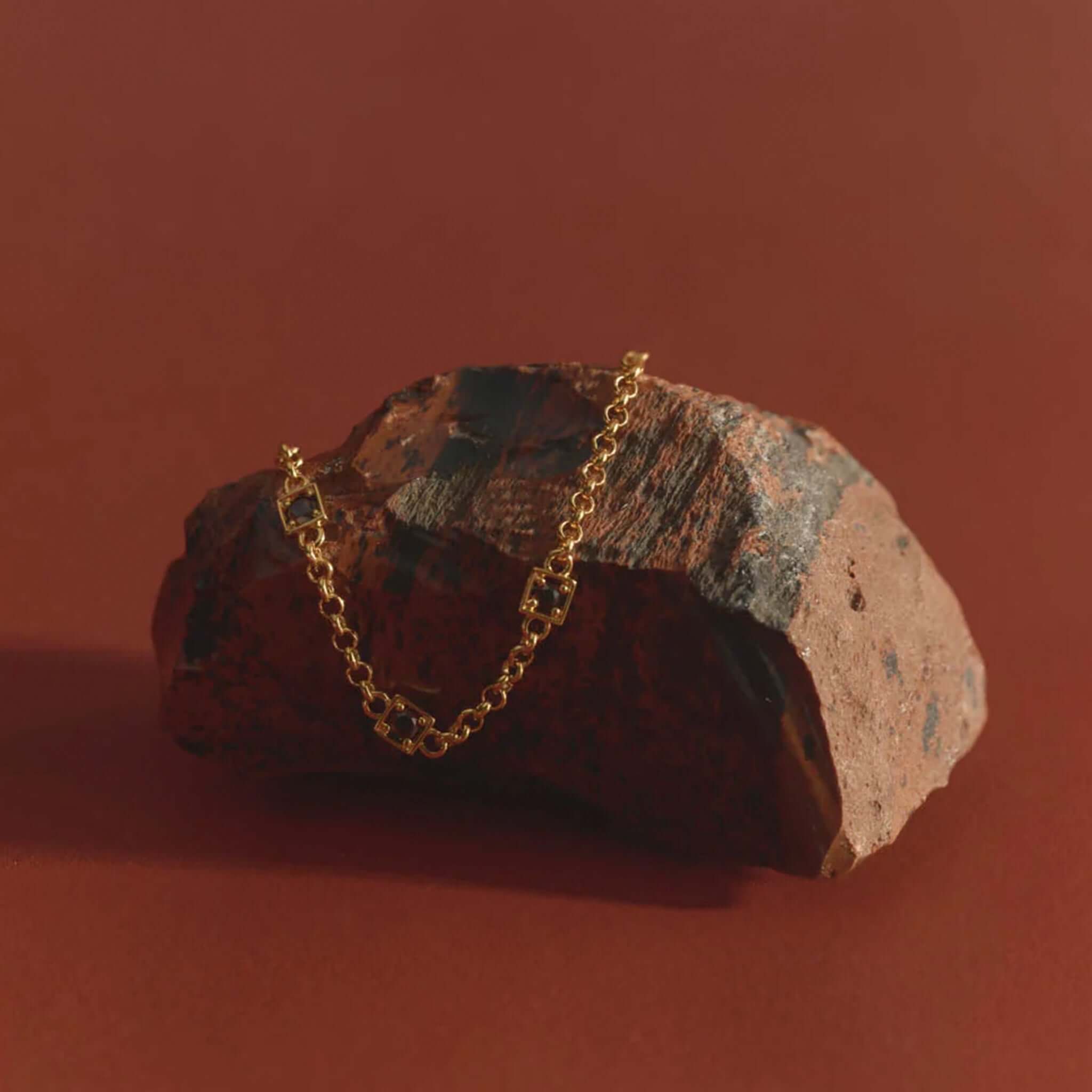 Kirstin Ash Ember Collection Renewal Bracelet - Gold Plated displayed on a textured rock backdrop, showcasing its elegance.