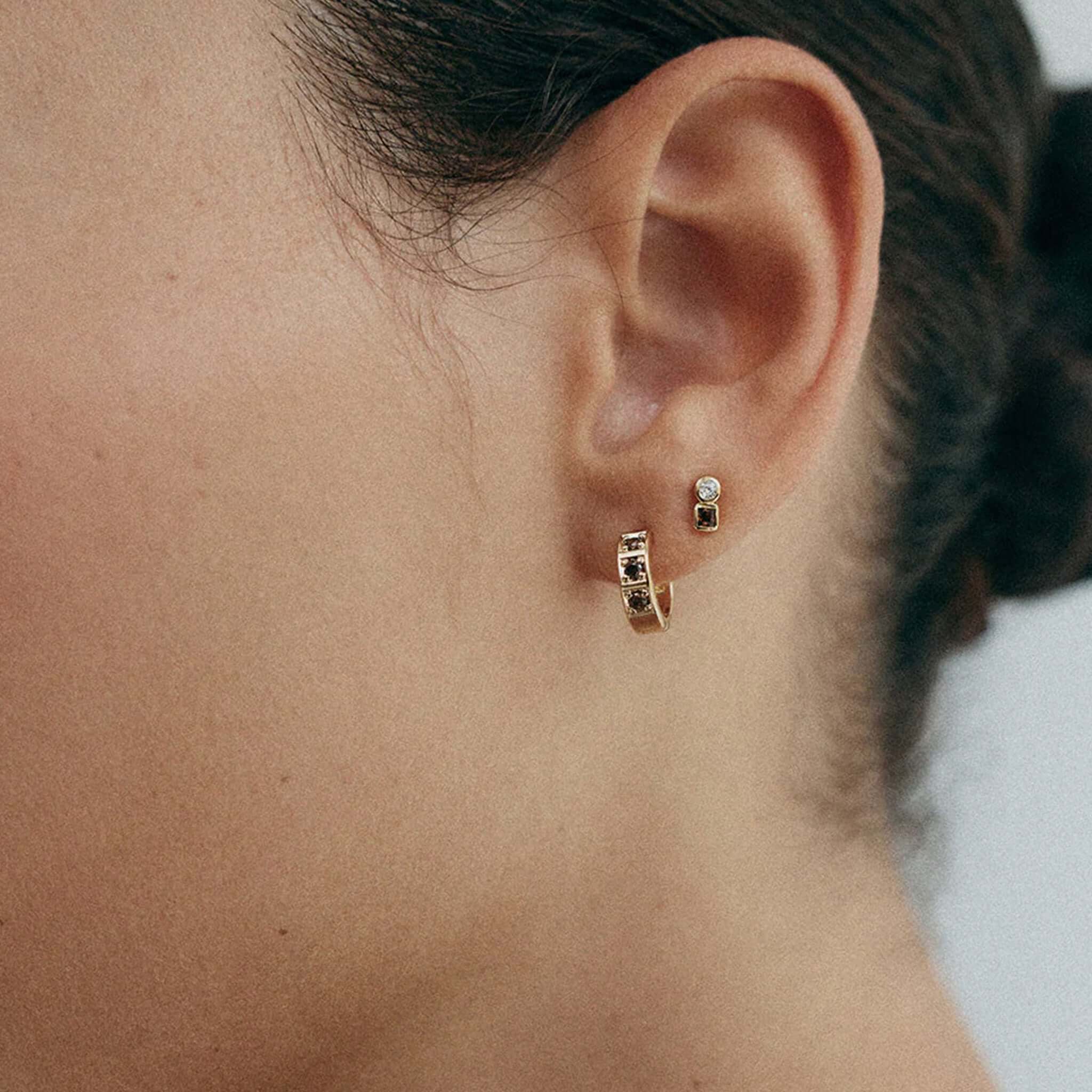 Kirstin Ash Ember Collection Renewal Huggie Earrings - Gold Plated worn by a model showing the earrings in an ear.