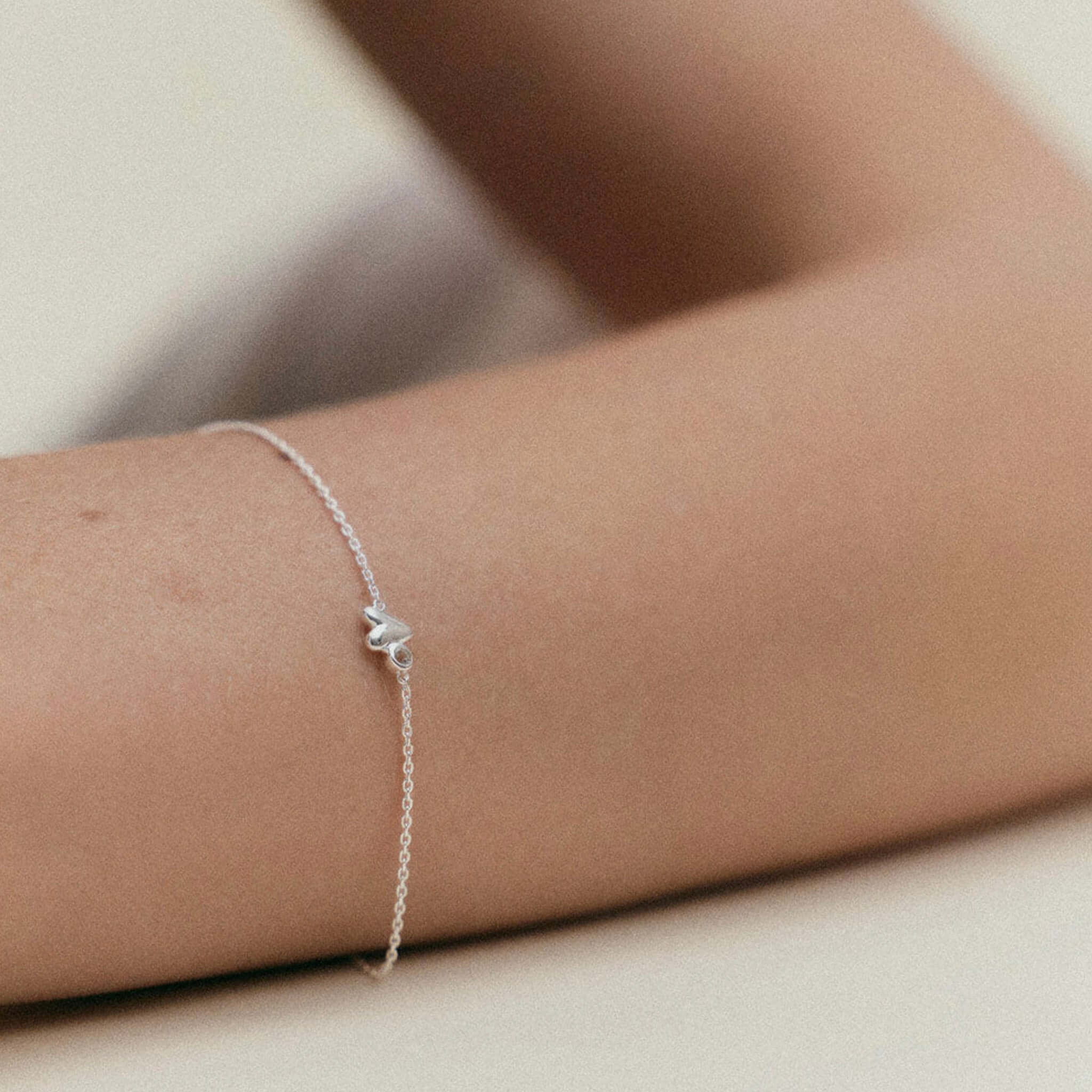 Alt Tag: Kirstin Ash Vista Collection Abode Heart Bracelet in sterling silver with organic heart charm on wrist, minimalist adjustable fine chain