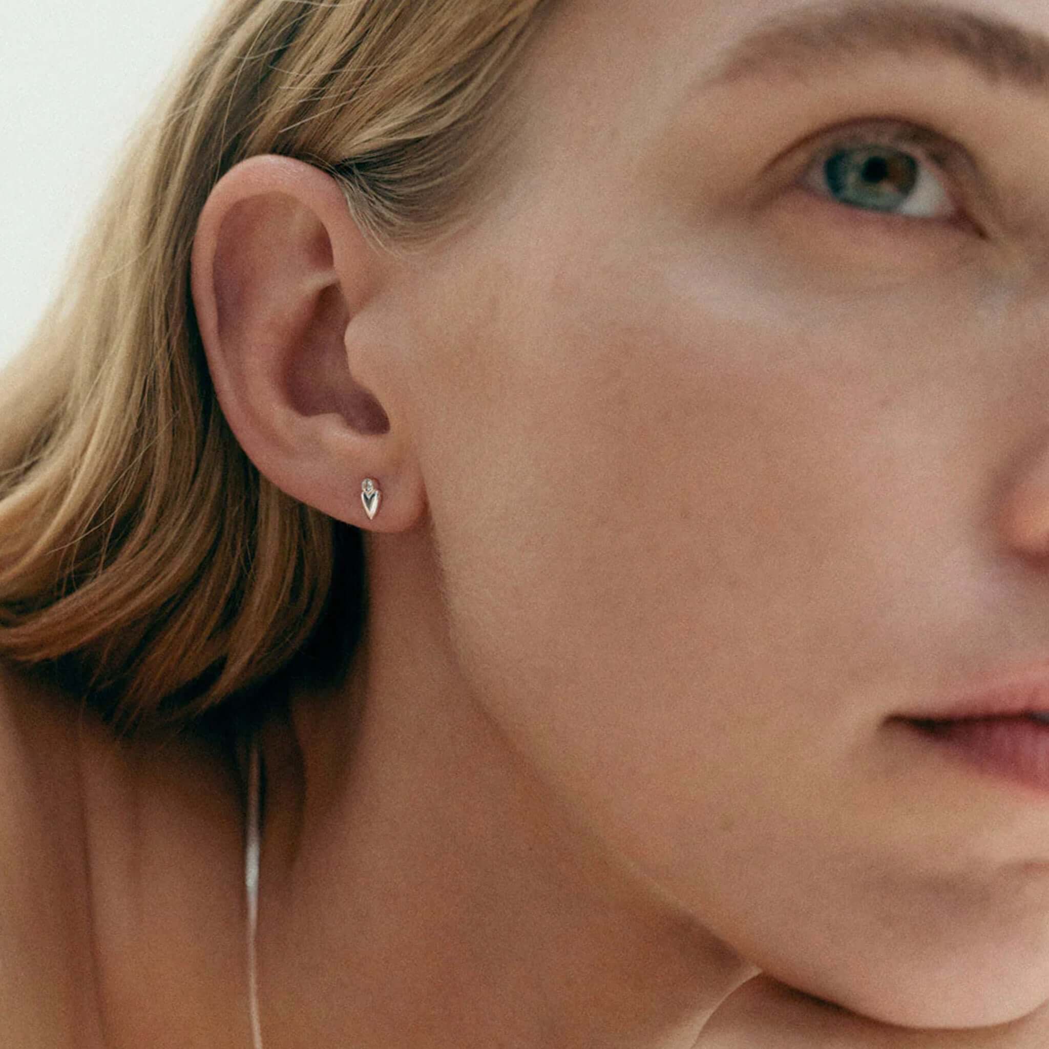 Alt Tag: Kirstin Ash Vista Collection Abode Heart Stud Earrings worn on ear, petite heart stud with white topaz gemstone