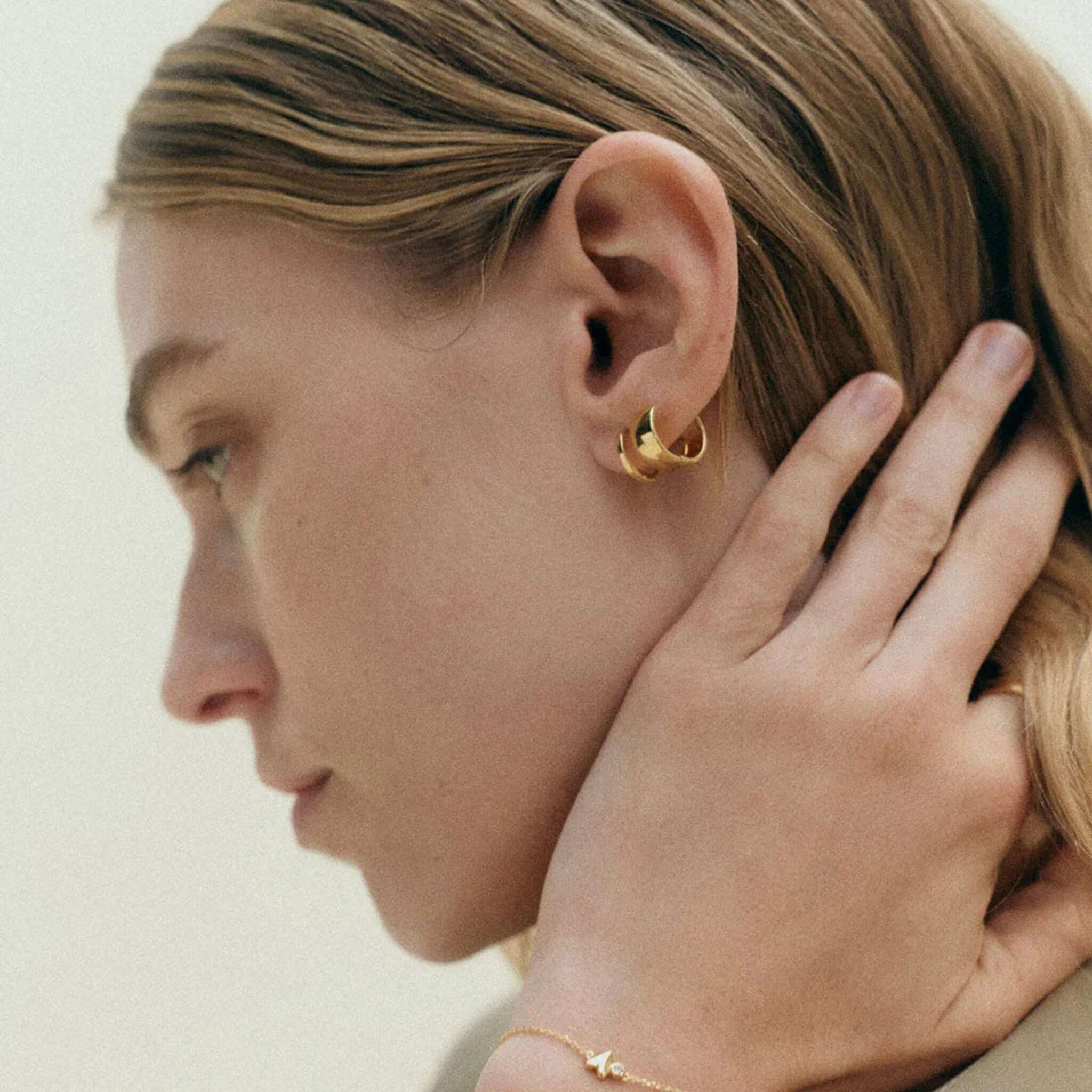 Alt Tag: Kirstin Ash Vista Collection Contour Huggie Earrings in sterling silver, lightweight polished huggie earrings worn on ear