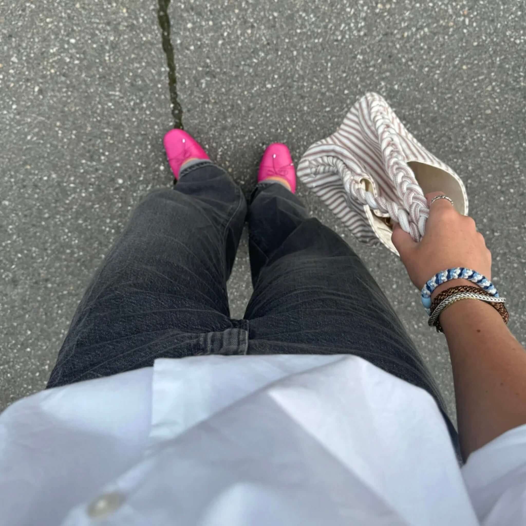 Alt Tag: Kknekki Hair Tie - Blue Silver Glitter bracelet stack on wrist, person holding striped clutch bag, pink shoes on asphalt