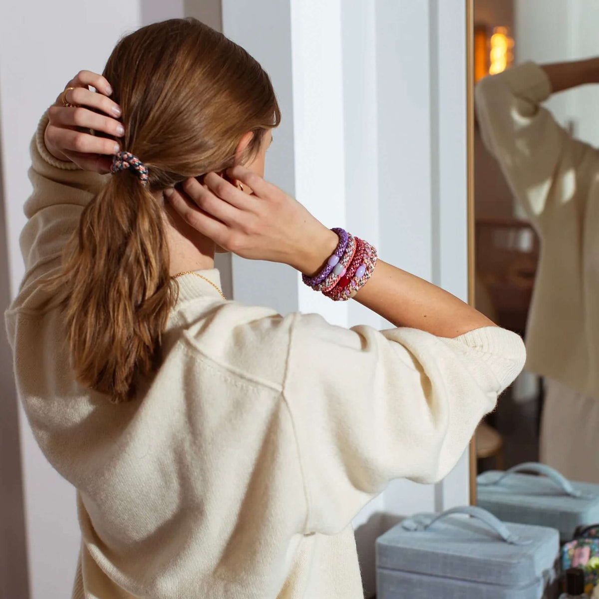Kknekki Hair Tie - Mix Turkish Beige Glitter worn by a woman styling her hair in front of a mirror.