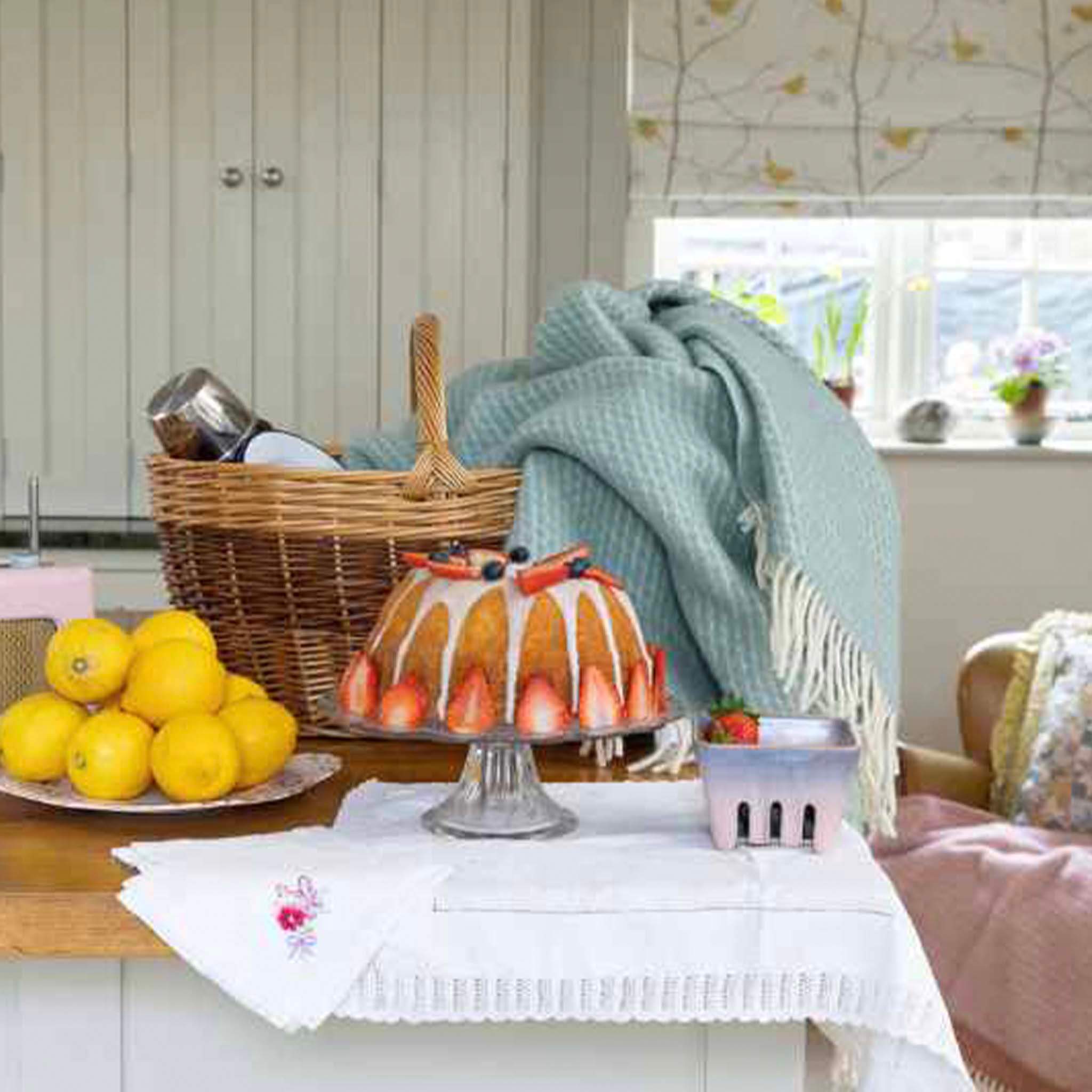 Klippan Yllefabrik Velvet Lambswool Throw - Duck Egg Blue draped over a basket in a cozy kitchen setting.