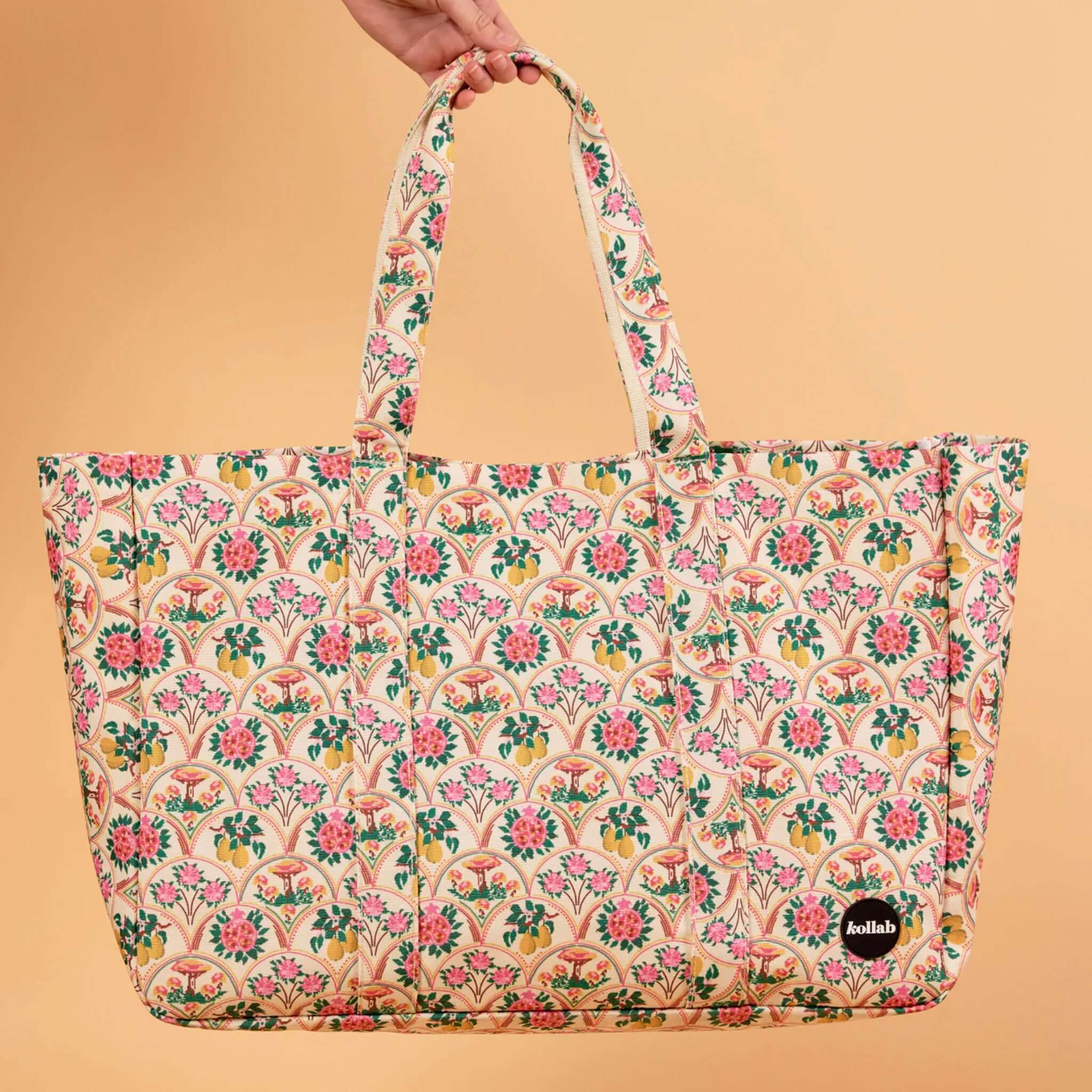 Floral patterned tote bag held by a hand against a beige background