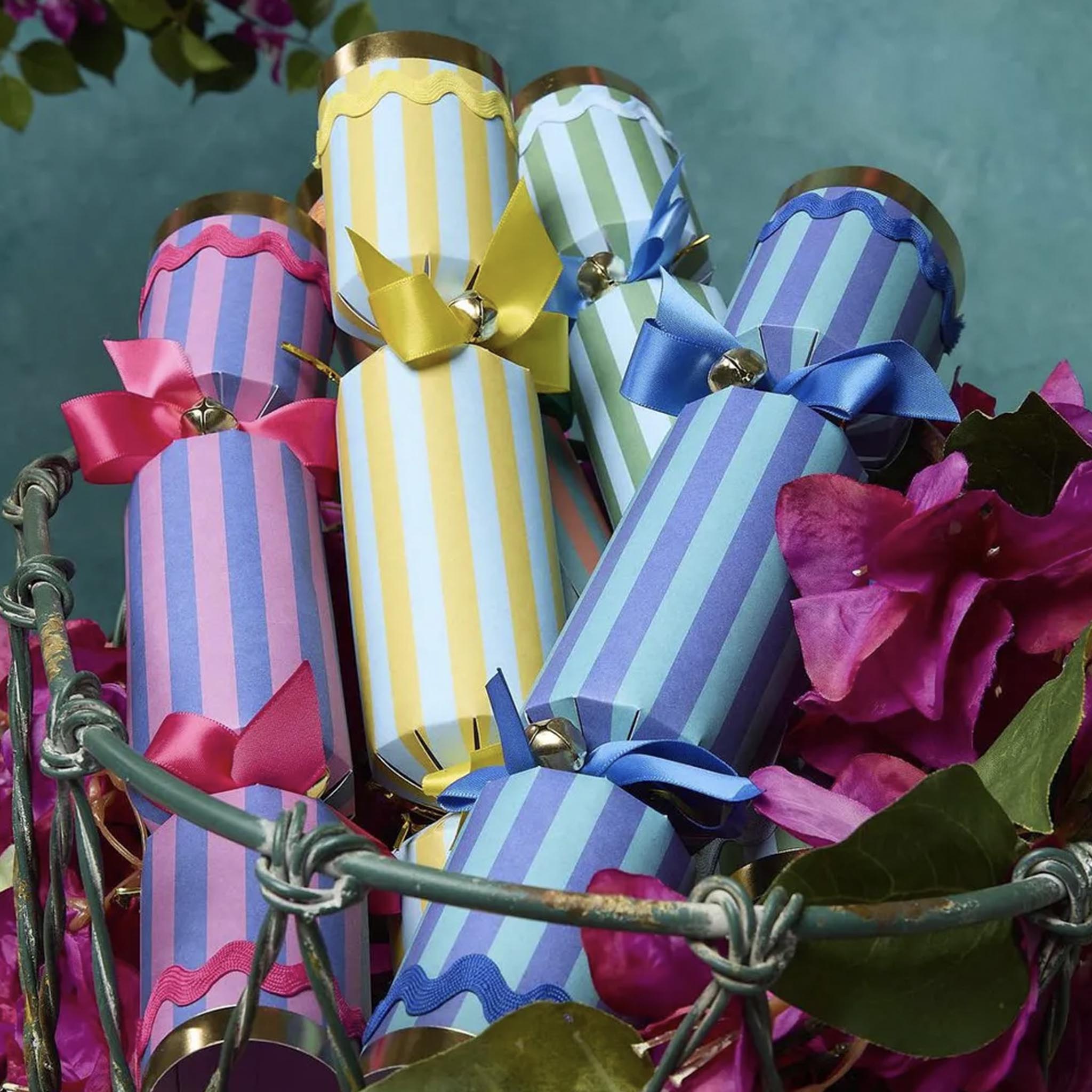 Colorful striped crackers with ribbons on a decorative stand surrounded by flowers.