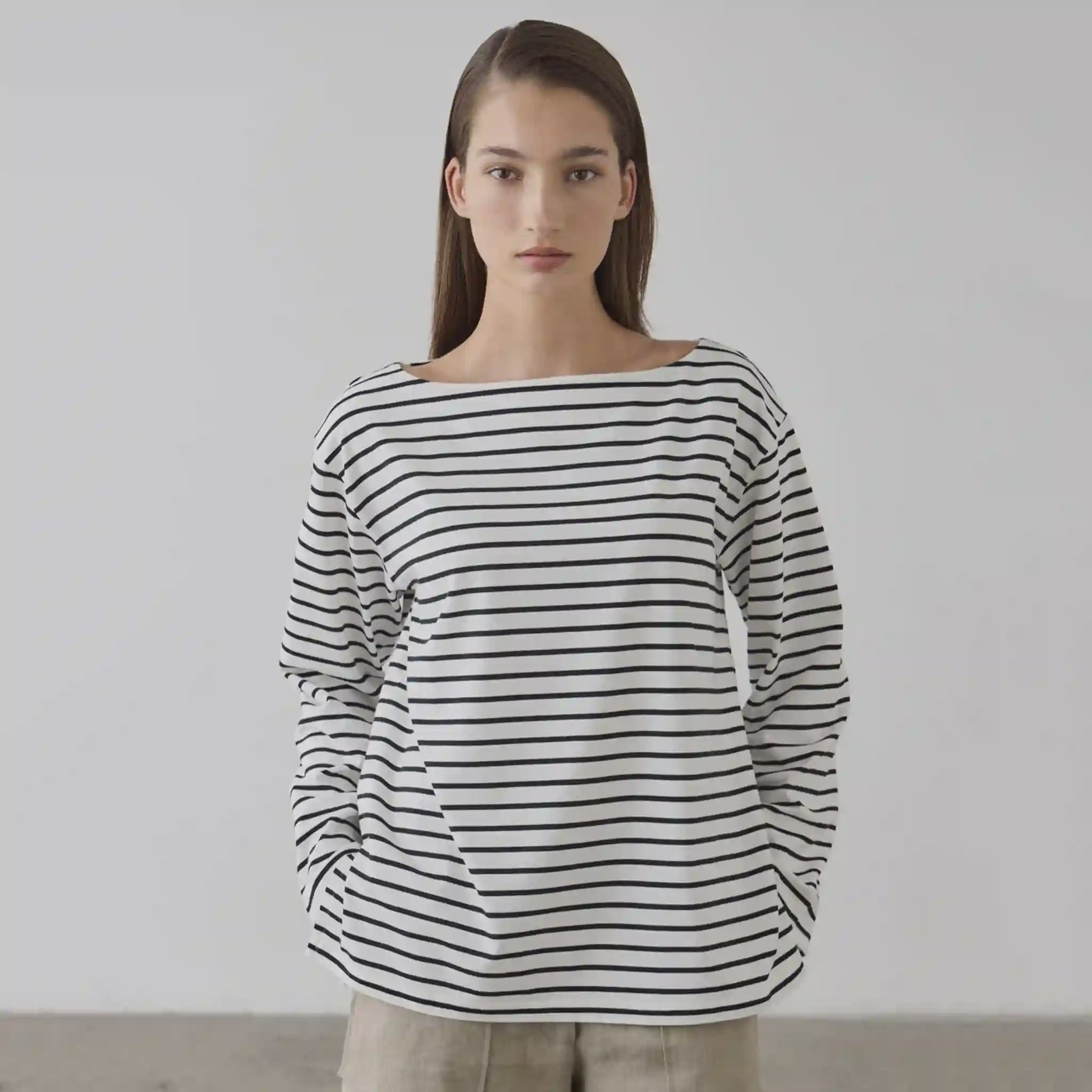 Woman wearing a black and white striped sweater against a plain background