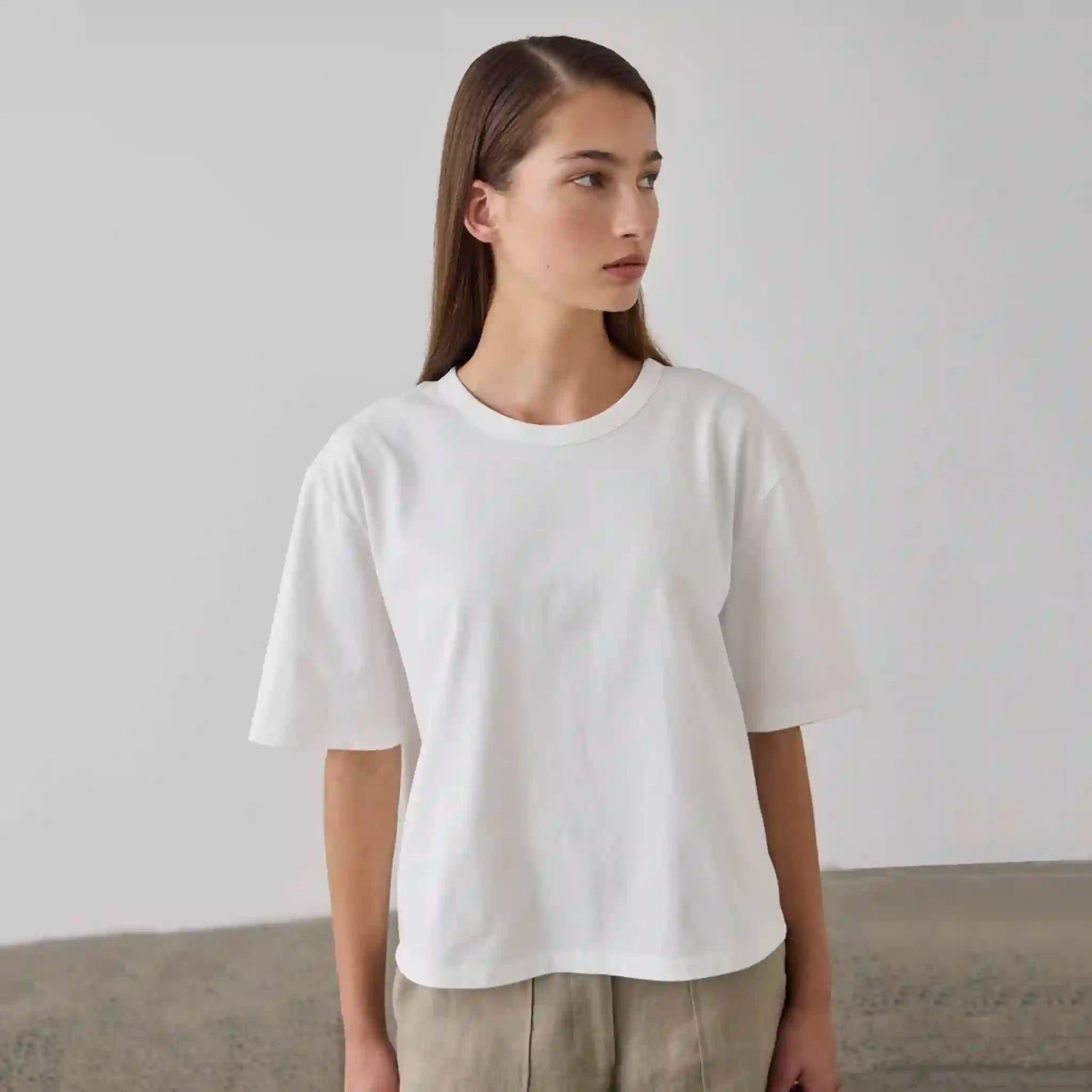 Person wearing a plain white t-shirt against a neutral background