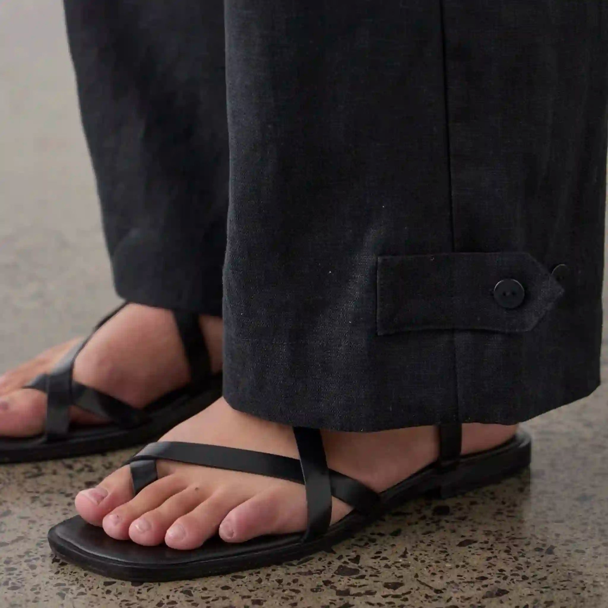 Person wearing black sandals with a plain background