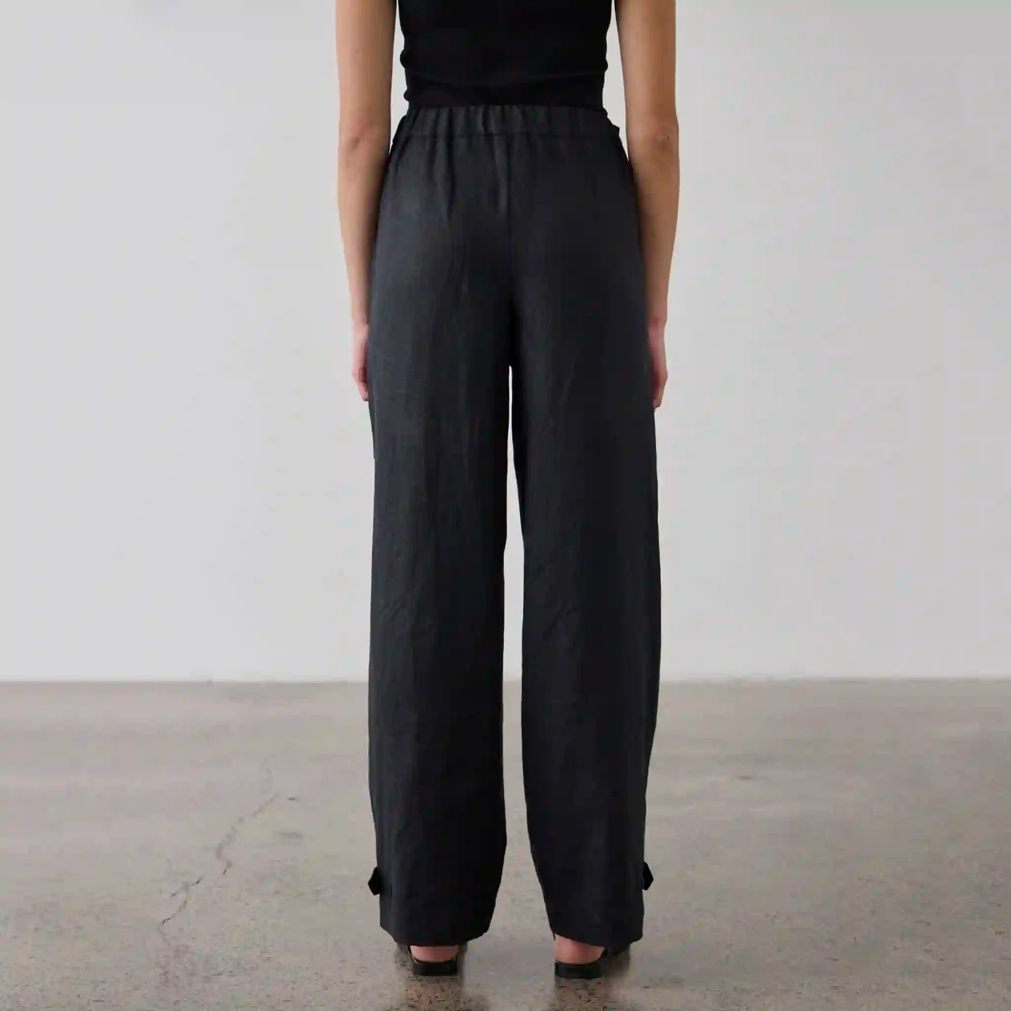Person wearing black wide-leg pants on a plain background