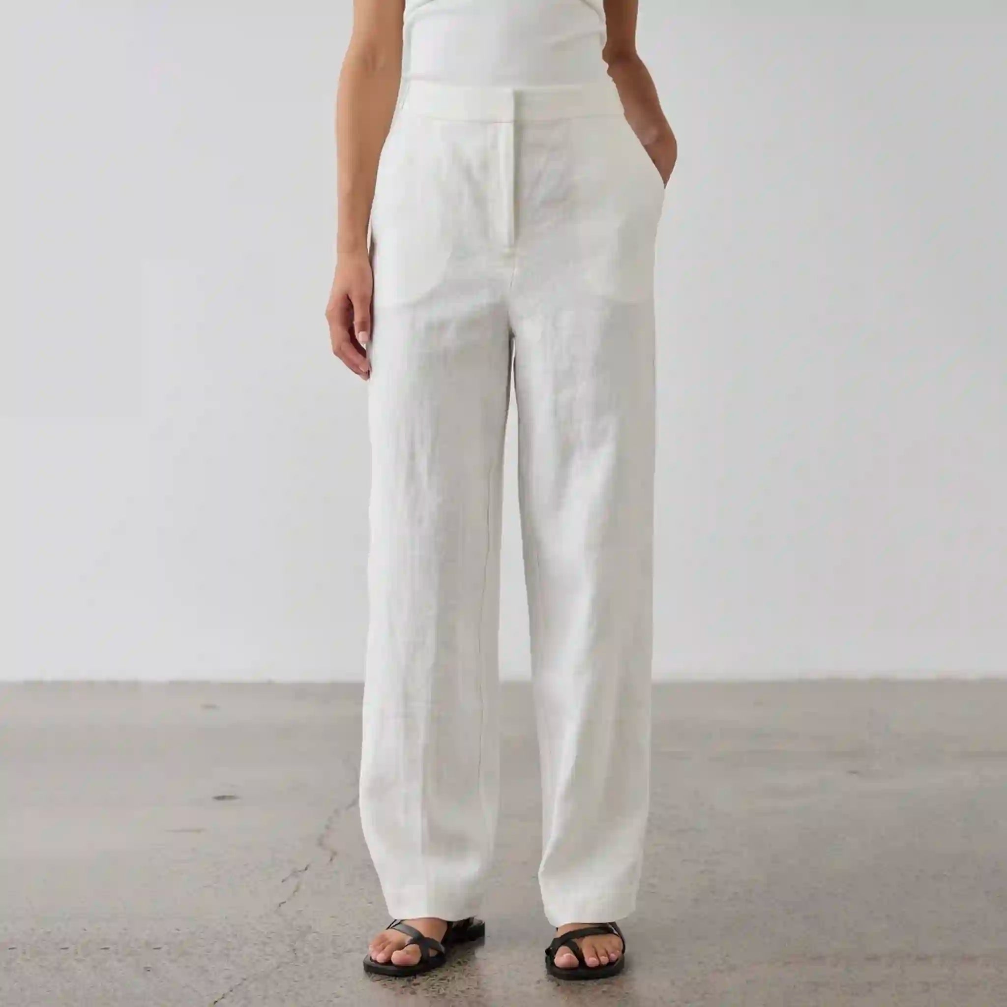 Person wearing white pants standing against a plain background