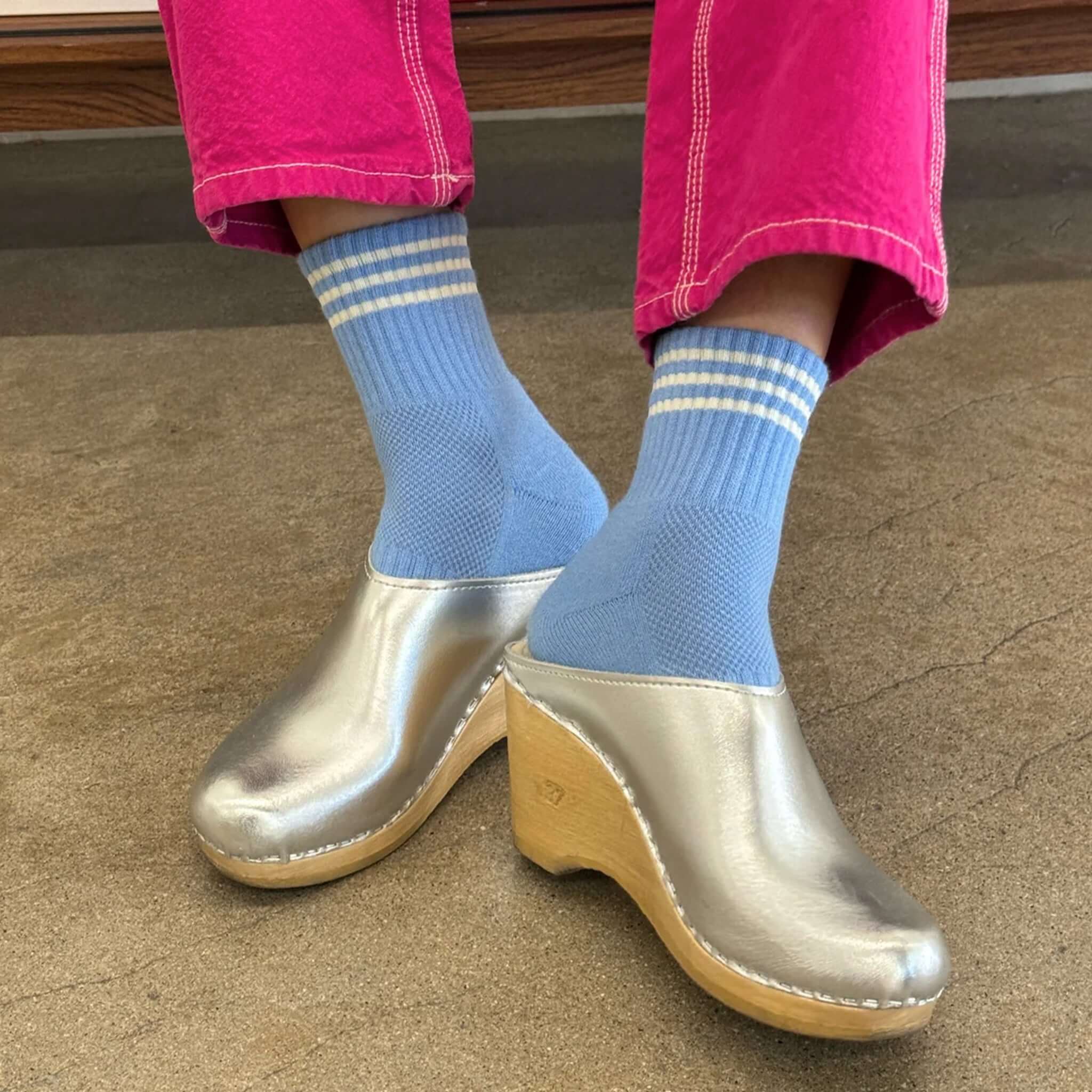 Le Bon Shoppe Girlfriend Socks - Parisian Blue worn with silver clogs and pink pants in a stylish setting.