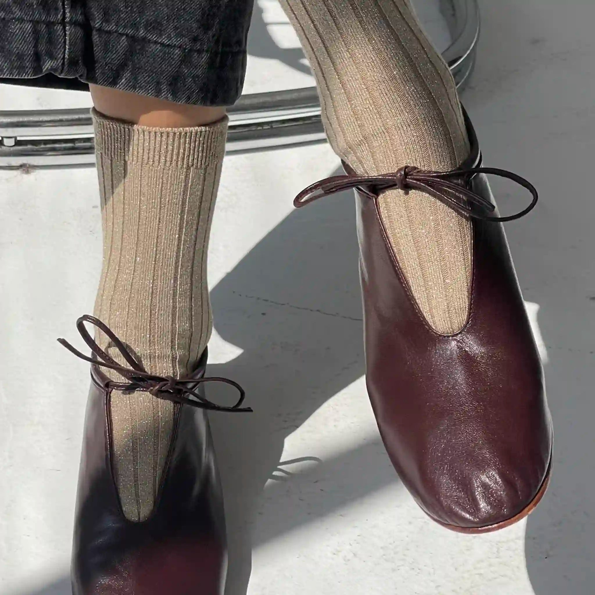 Brown leather shoes with ribbed socks on a light background