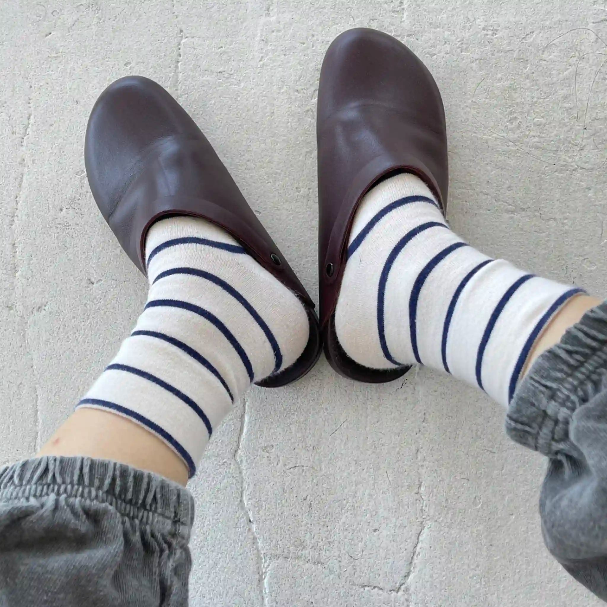 Brown shoes and striped socks on a light gray floor