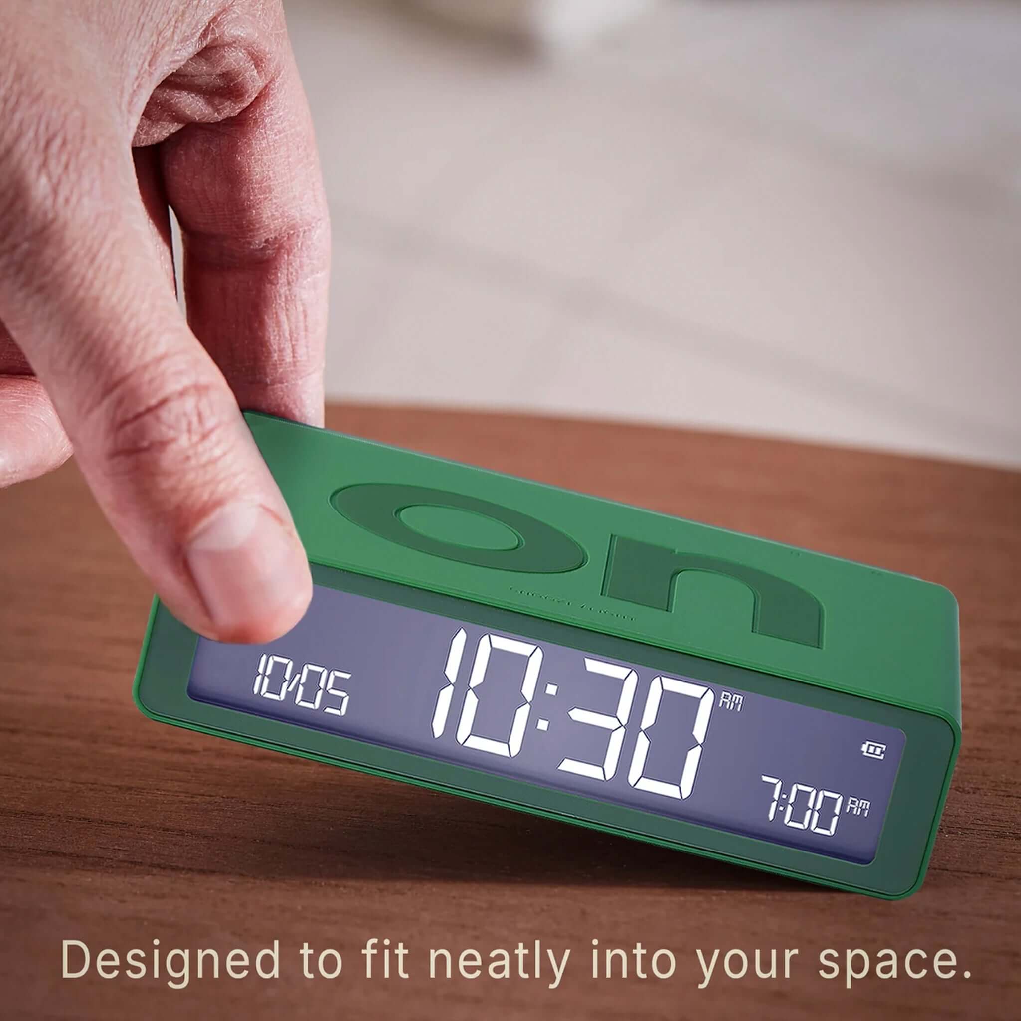Lexon Flip Classic Reversible LCD Alarm Clock - Emerald Green displayed on a bedside table.