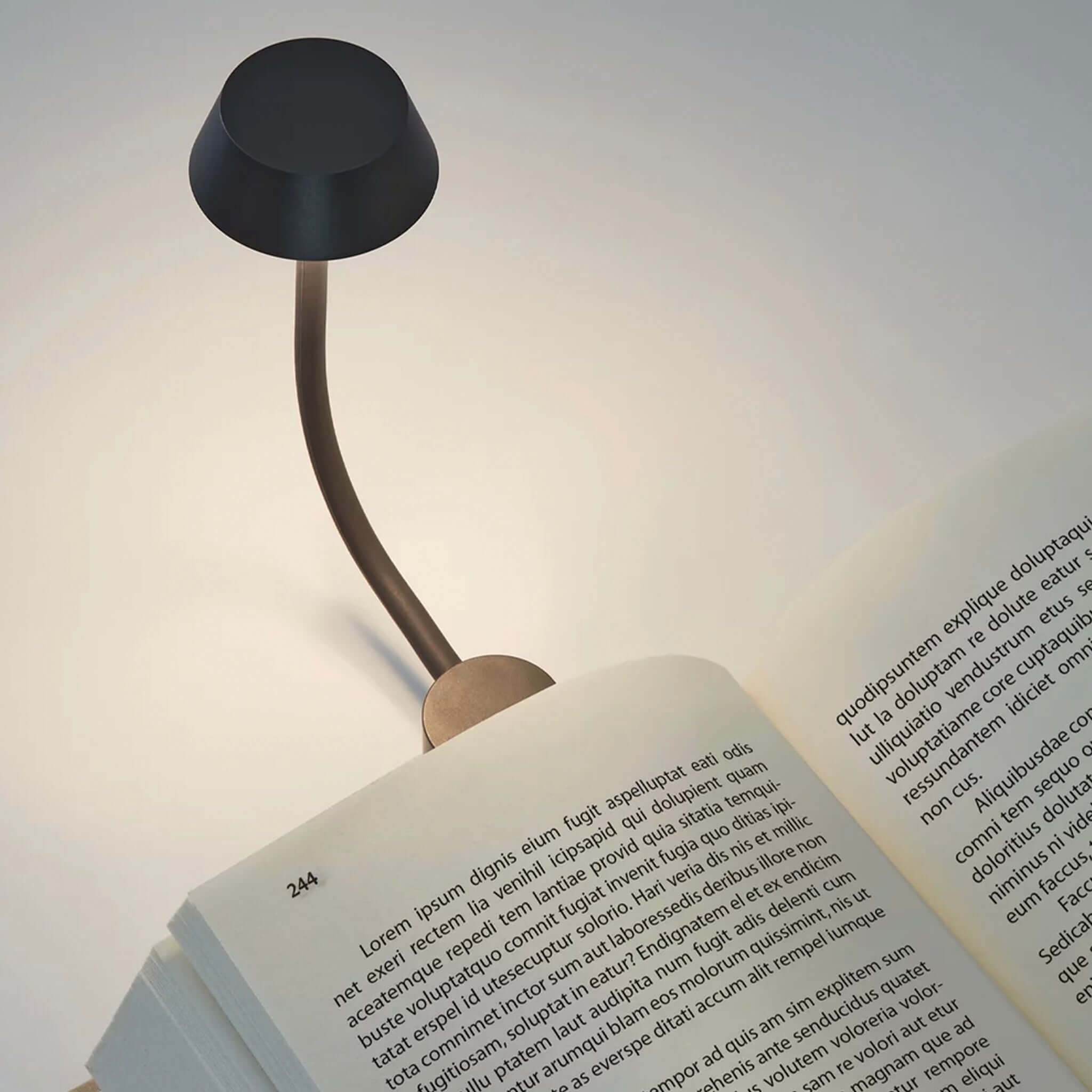 Lexon Mimi Clip-on Reading Lamp - Gunmetal illuminating an open book with a sleek design.